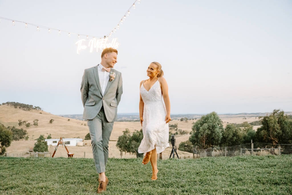 Sally and Luke under festoon lights and their neon sign on the family property at Chintin