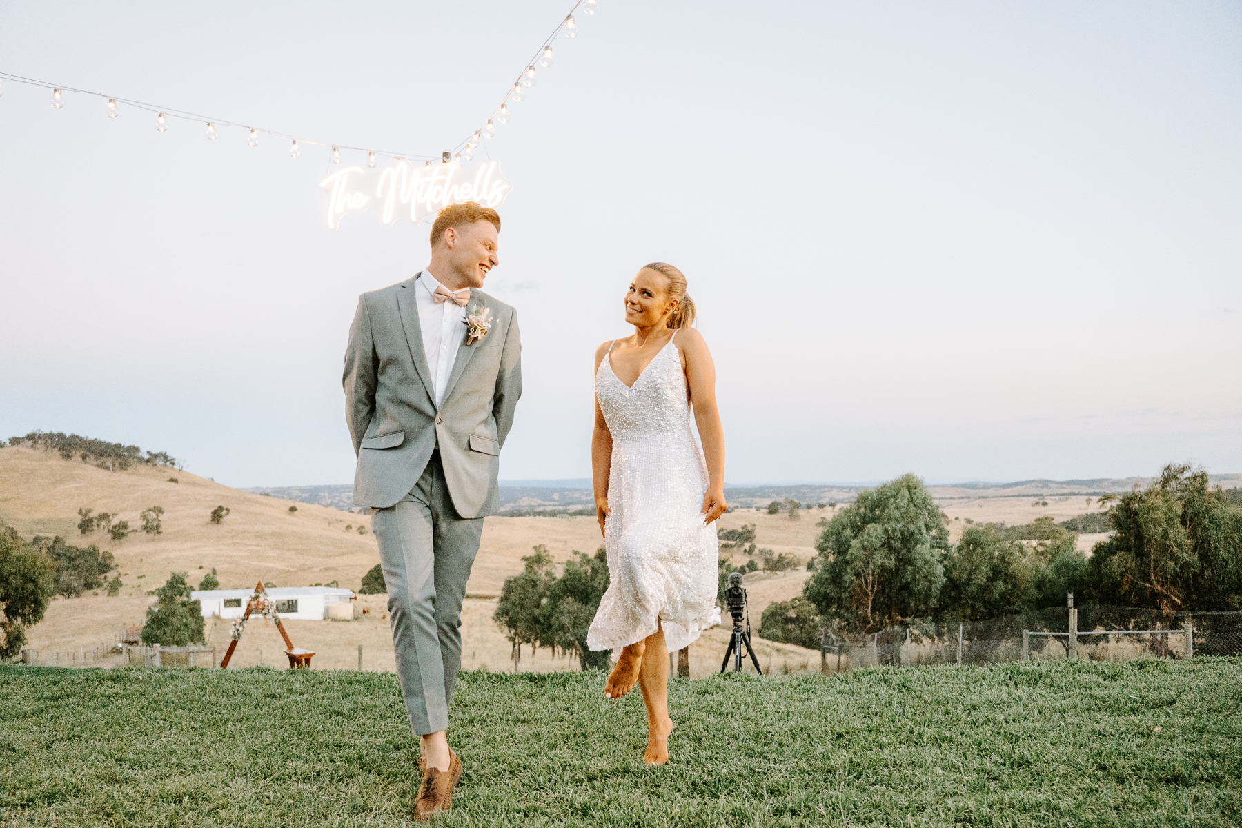 Sally and Luke under festoon lights and their neon sign on the family property at Chintin
