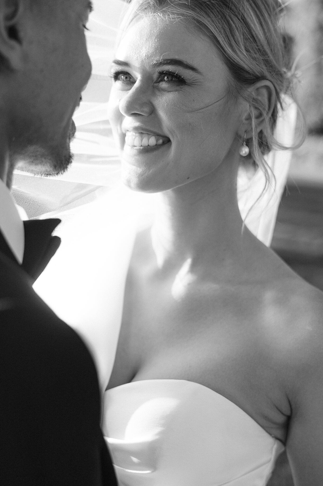 Black-and-white close-up of Georgie smiling up at Johnny, her veil behind her.