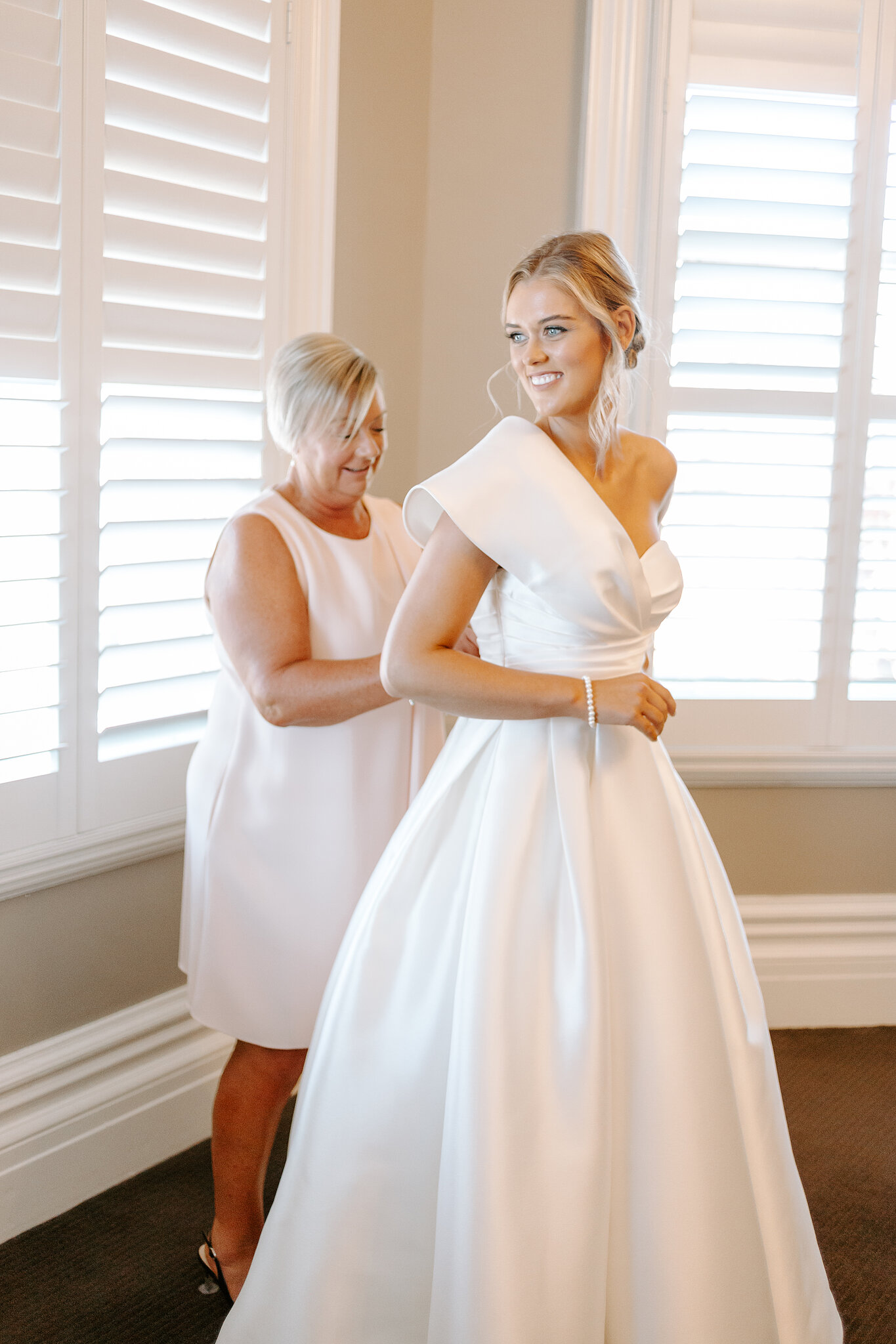 A loved one fastens Georgie’s gown by the shuttered bay windows at Ballarat Premier Apartments.