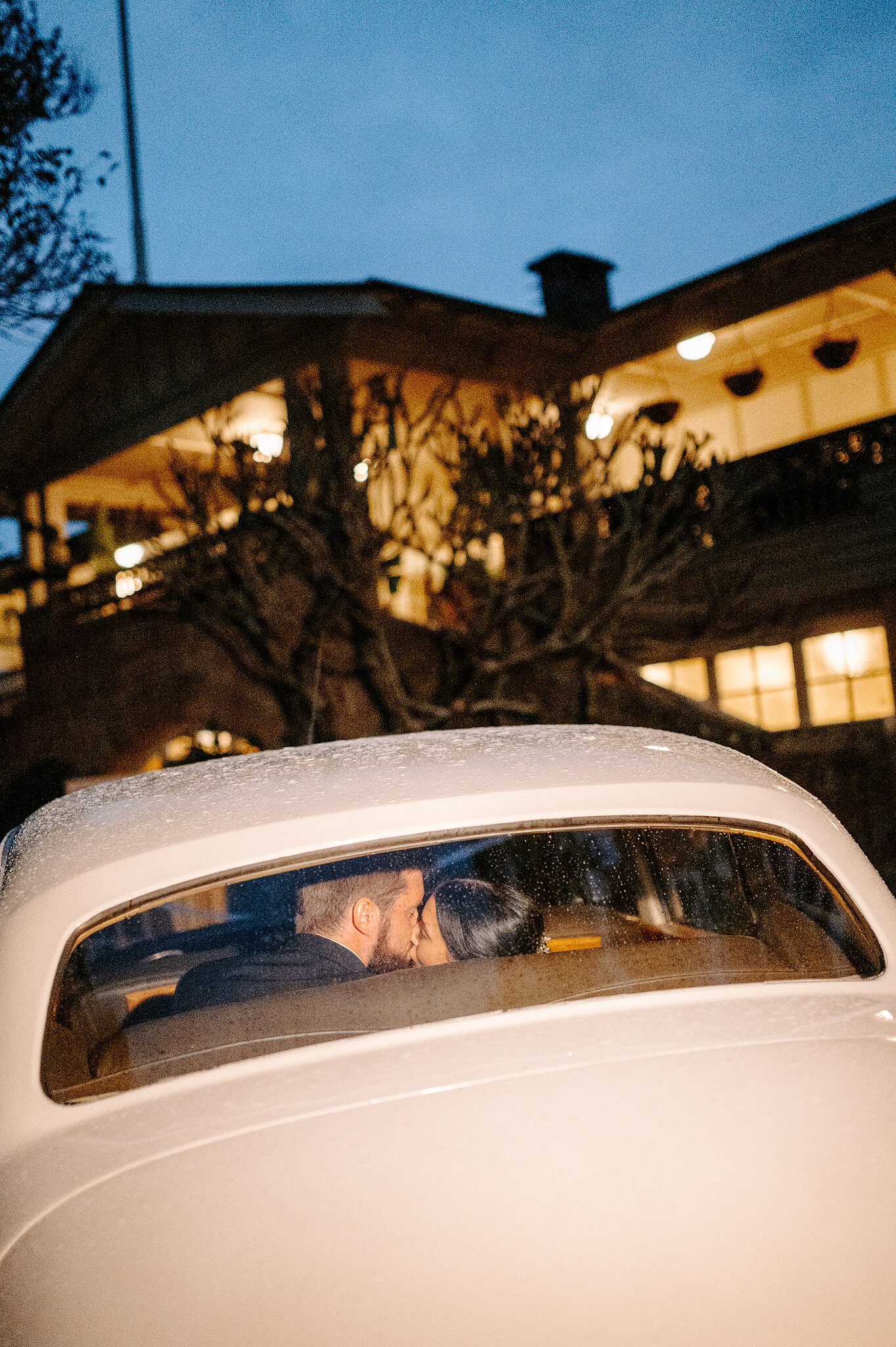 Alexa and Chris steal a kiss in the back of the rain-speckled Rolls-Royce as Burnt Orange glows at blue hour.