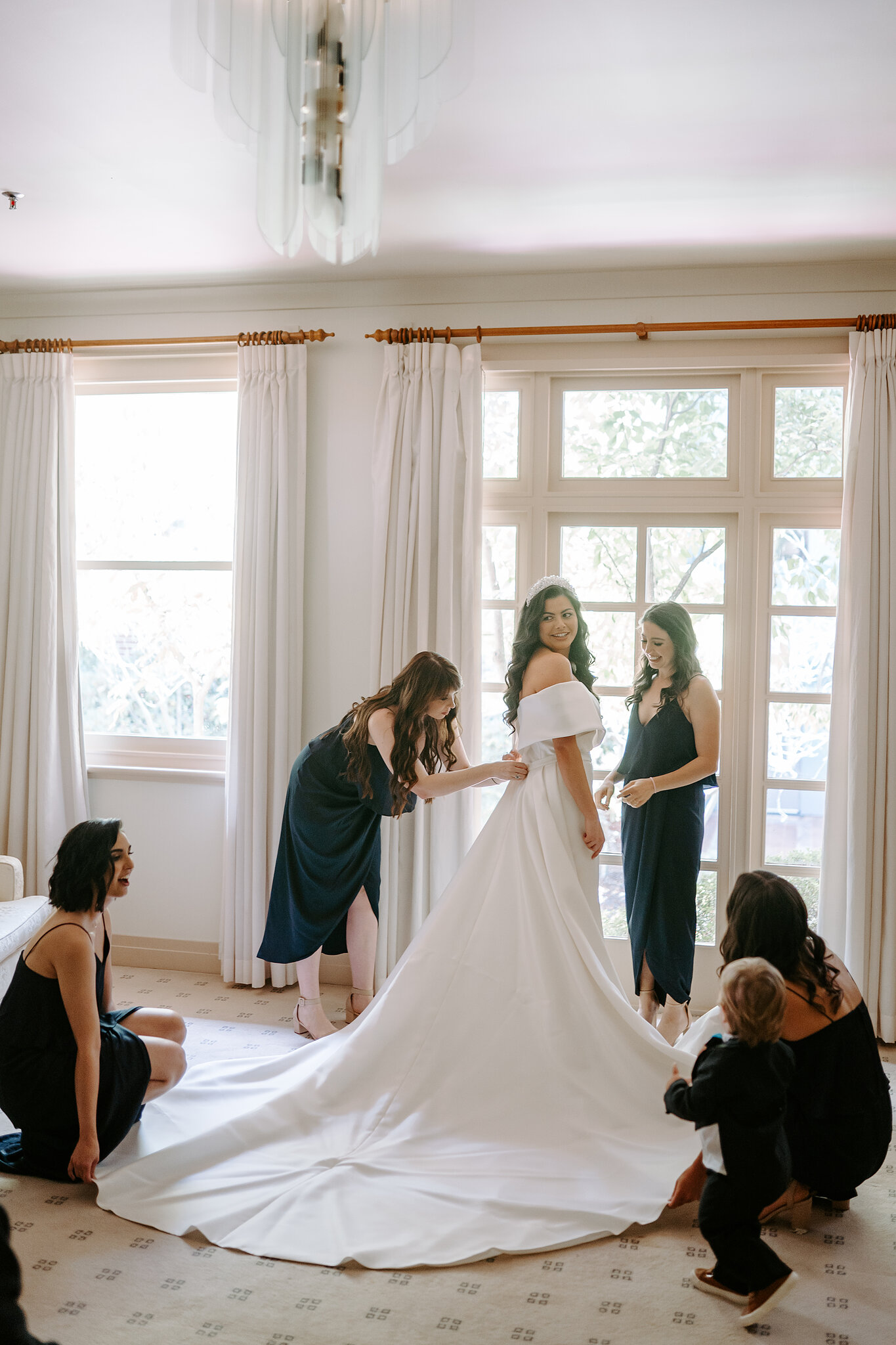 Wedding attendants arrange Helena’s gown and train during preparation at Hyatt Hotel Canberra.