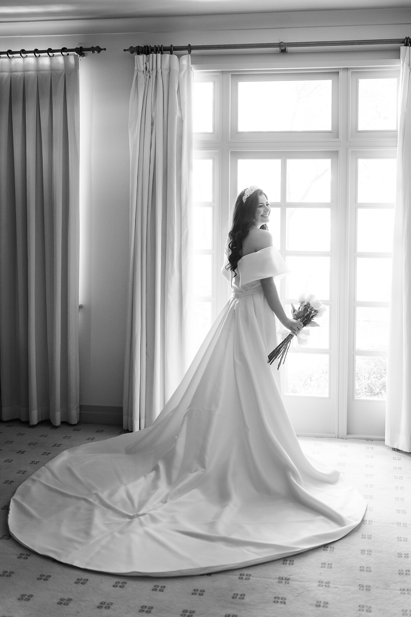 Helena holds a white rose bouquet beside a window at Hyatt Hotel Canberra.