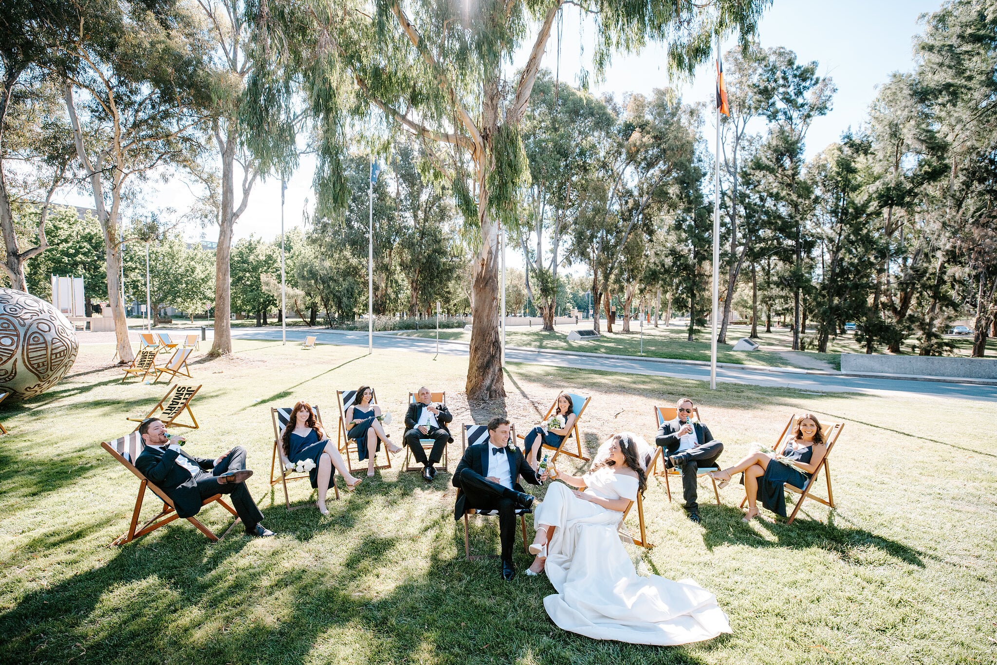 Helena and Xavier sit with their wedding party on a garden lawn in Canberra.