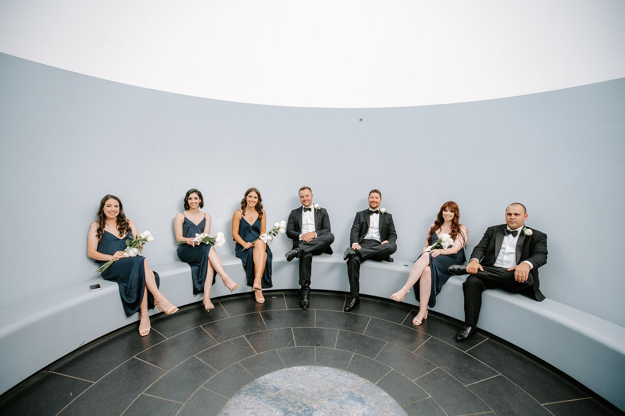 Wedding attendants sit on the curved bench inside James Turrell’s Within without, open to the sky above.