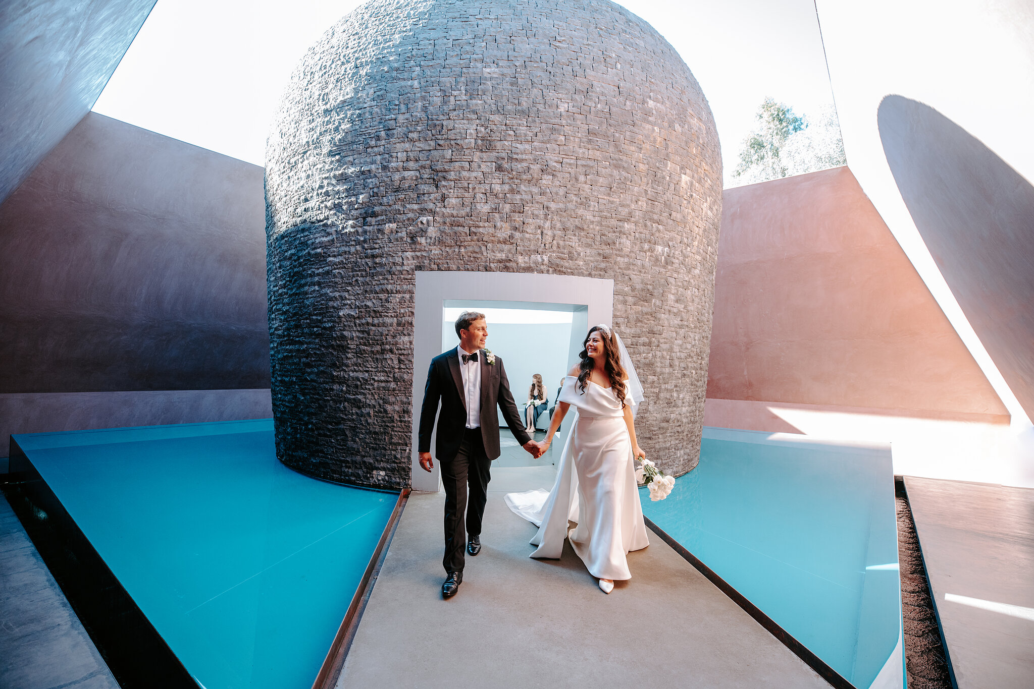 Helena and Xavier walk out from the stone dome between the turquoise pools of the Within without Skyspace.