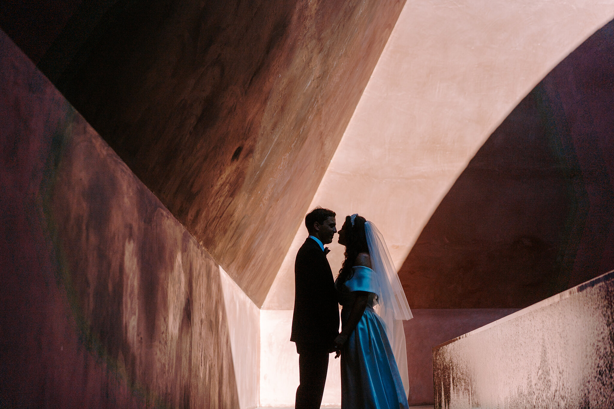 Helena and Xavier kiss in silhouette beneath the sloping walls of the Within without Skyspace in Canberra.