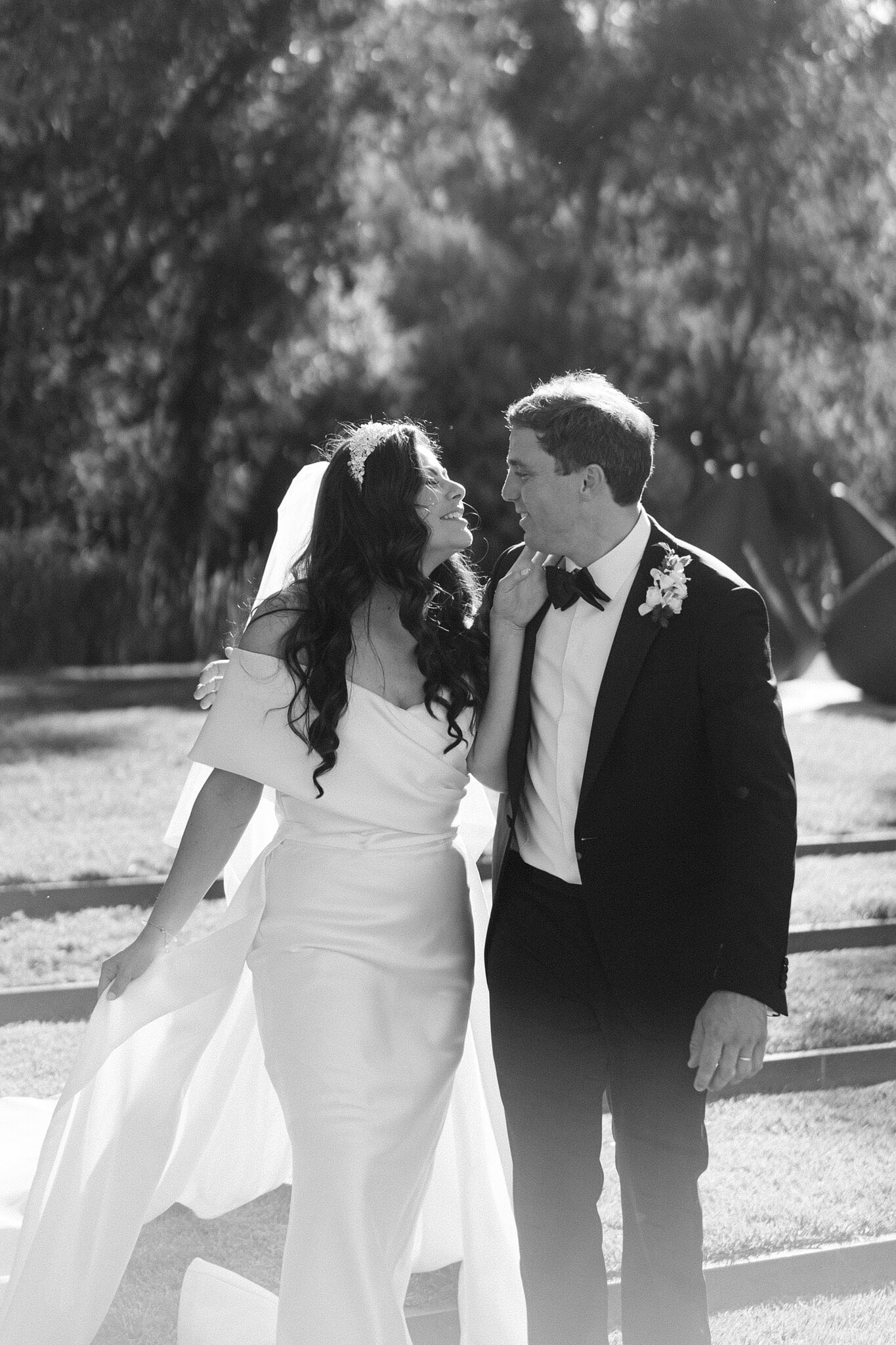 Black-and-white portrait of Helena and Xavier looking at each other beneath Canberra garden trees.