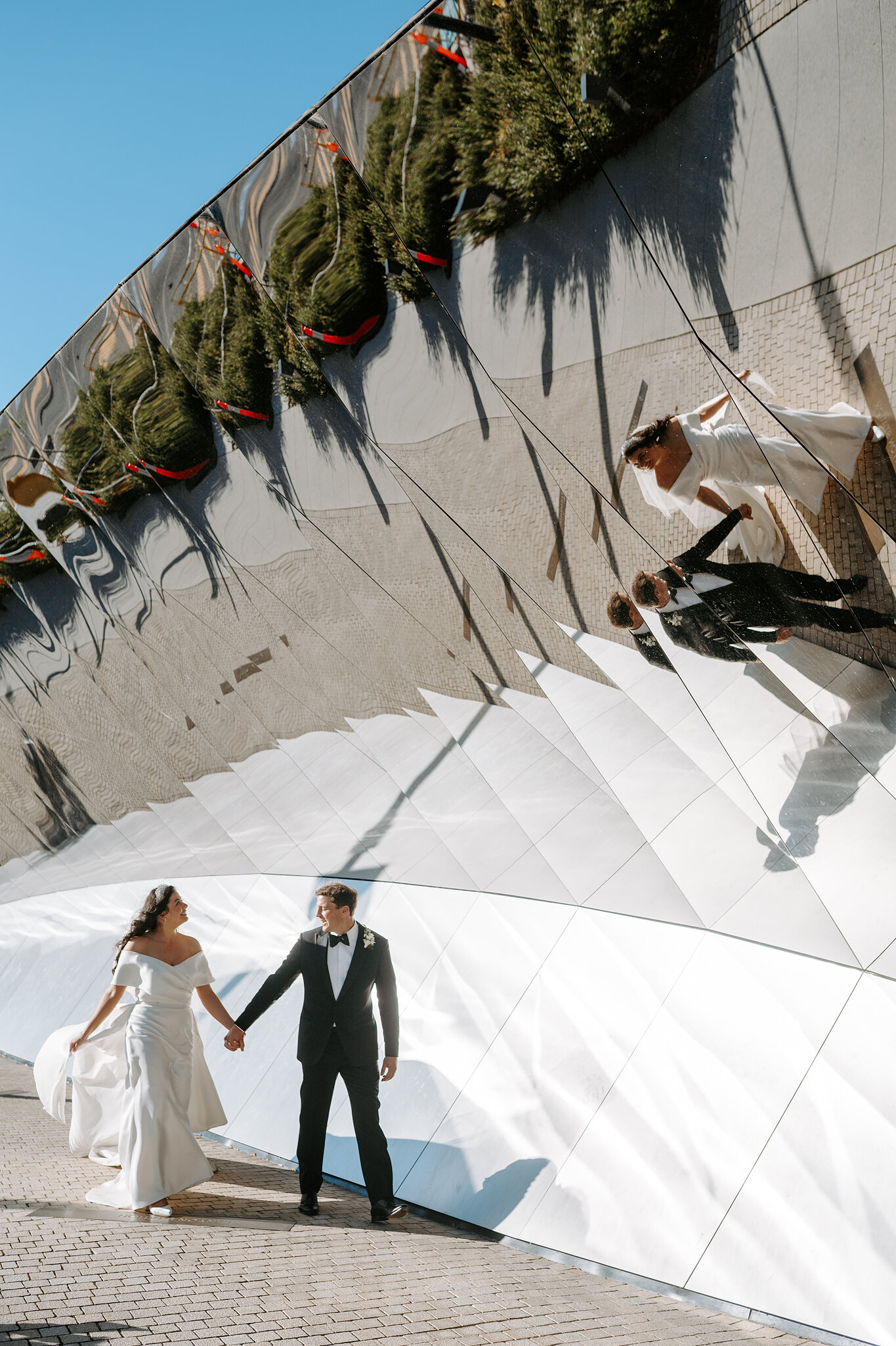 Helena and Xavier pose beside their reflections in the National Museum of Australia Welcome Wall.