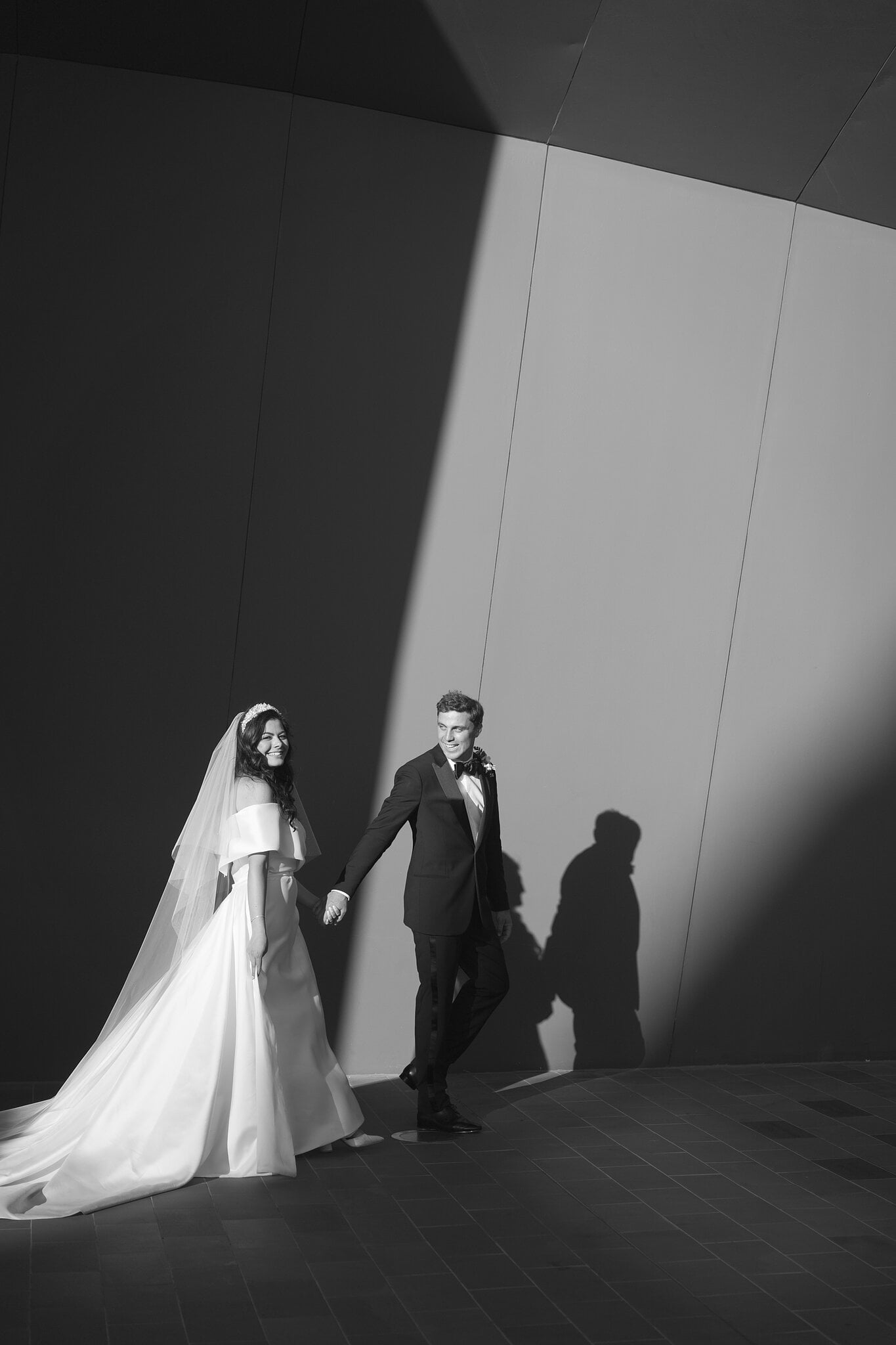 Helena and Xavier walk along a sunlit wall at the National Museum in Canberra.