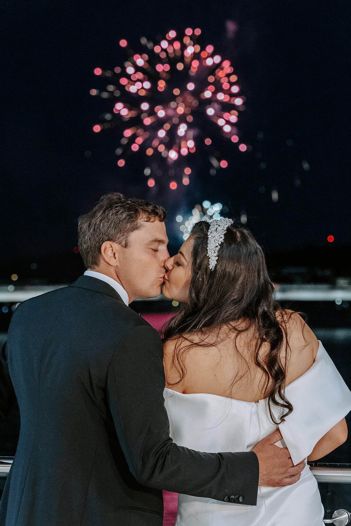 Helena and Xavier kiss beneath pink fireworks during their National Museum celebration in Acton.
