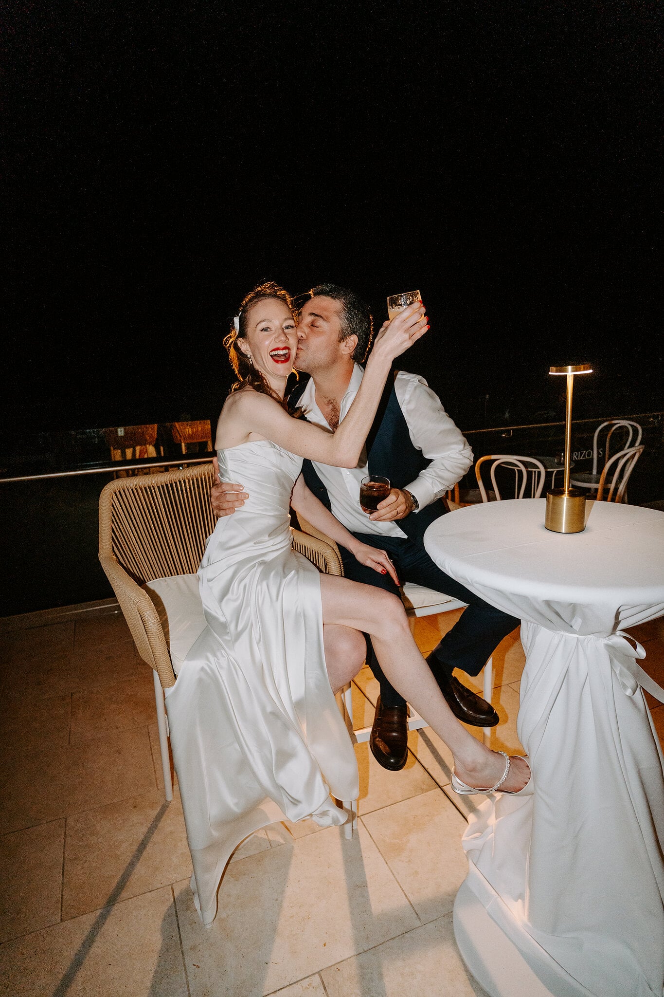 A cheek kiss and a raised glass on the balcony at Horizons South Maroubra after dark.