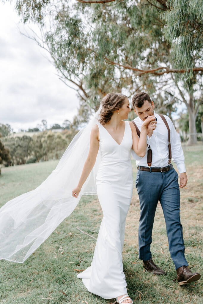 He kisses her hand as they walk the lawn under the gums at Inglewood Estate, Yarra Valley