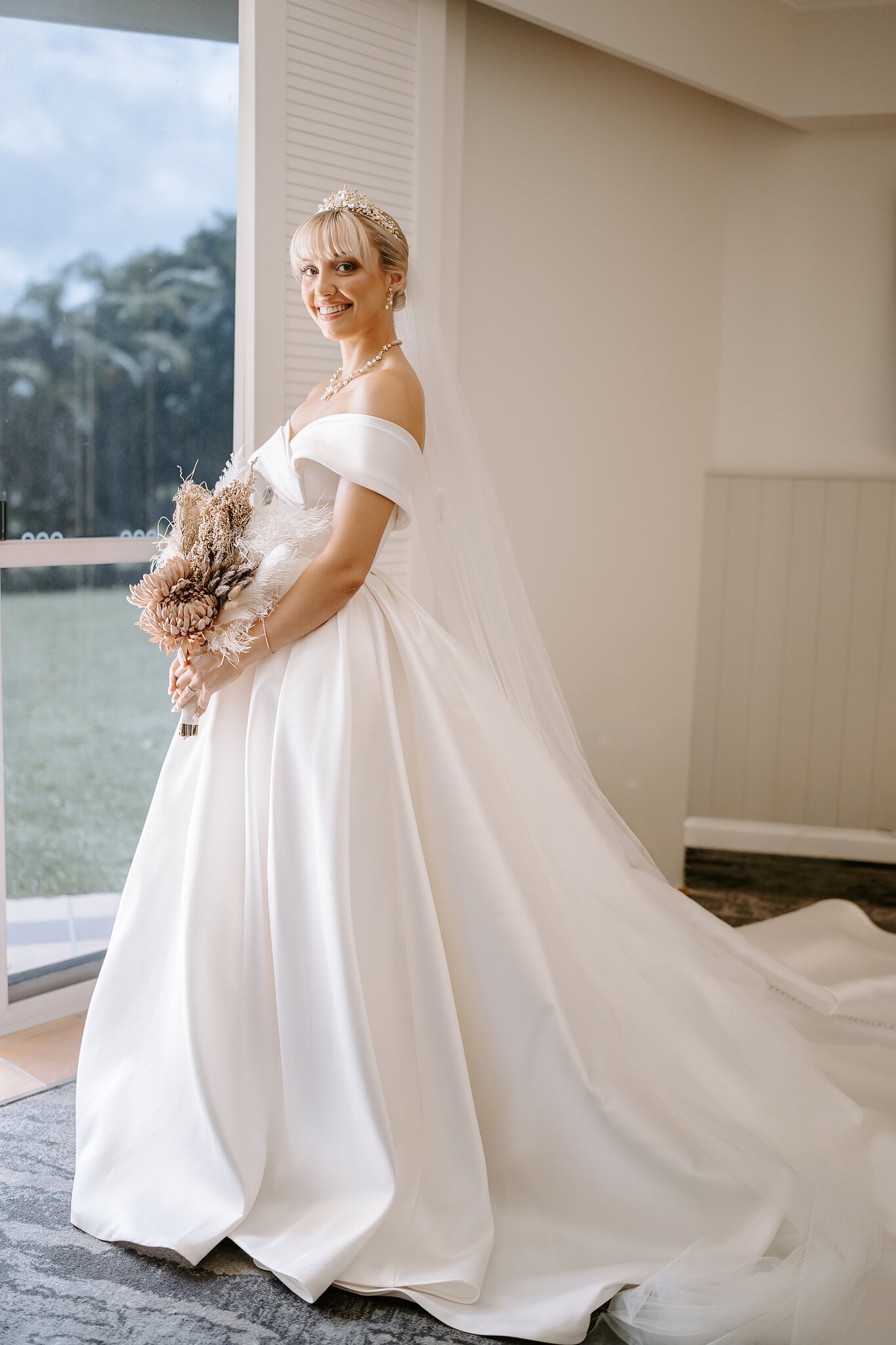 Ashley holds her dried-flower and pampas bouquet beside the window of her suite.