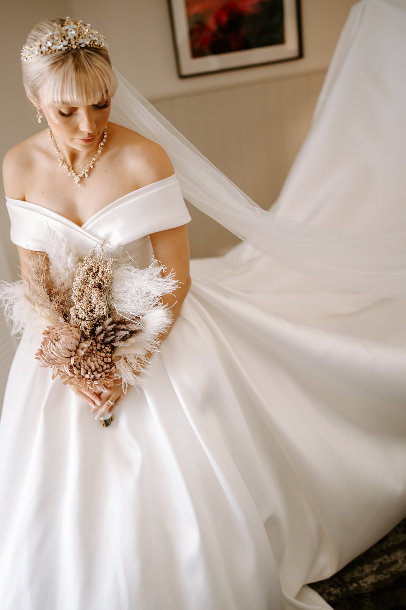 Ashley looks down at her bouquet as her long veil sweeps out behind her.