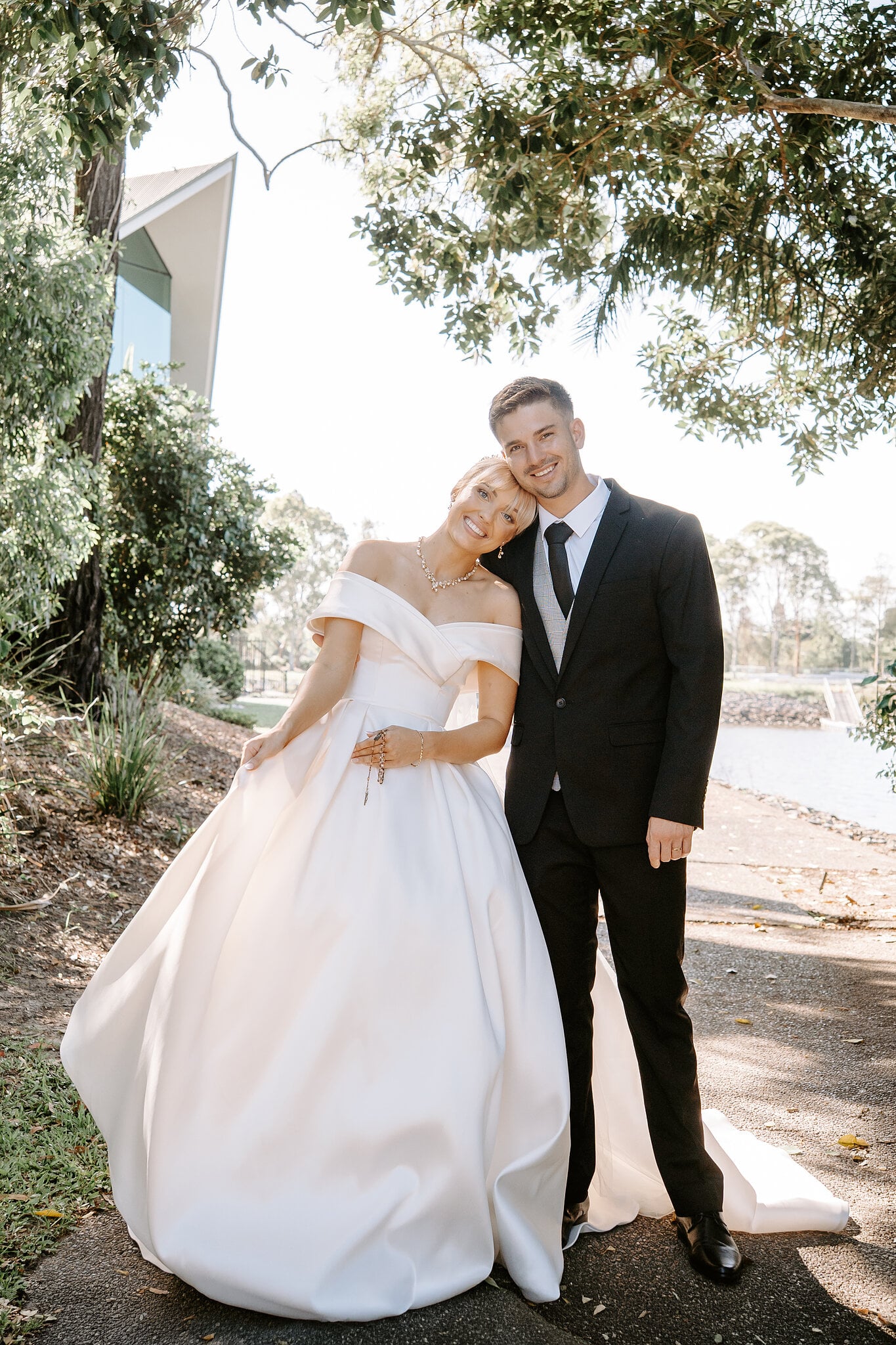 Heads together under the trees beside the water, Ashley’s satin skirt spread wide.