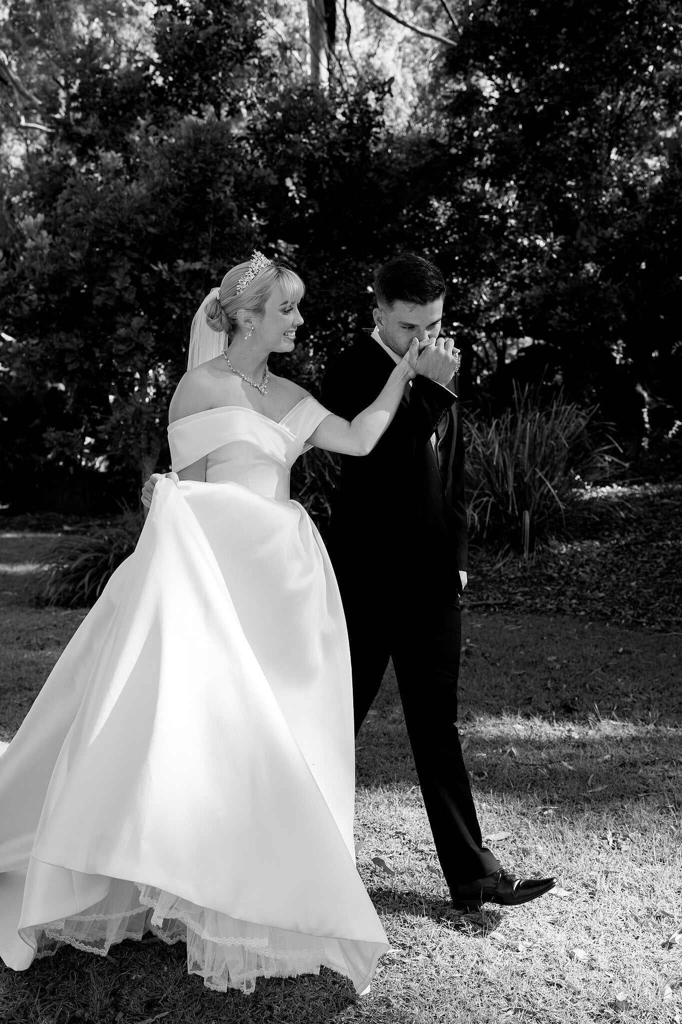 Lane kisses Ashley’s hand as they walk through the dappled garden shade.