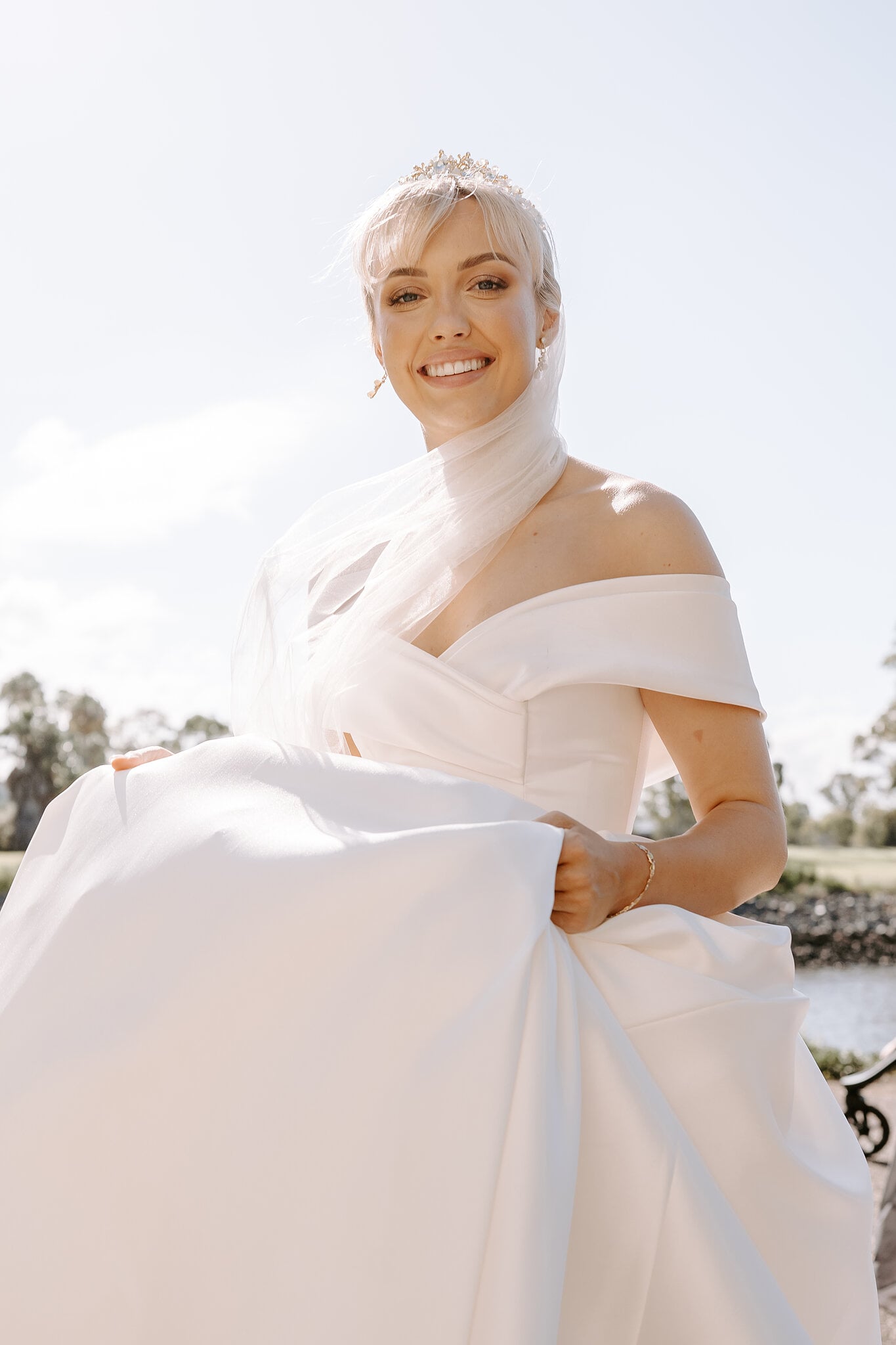 Ashley smiles into the summer sun, lifting her satin skirt.