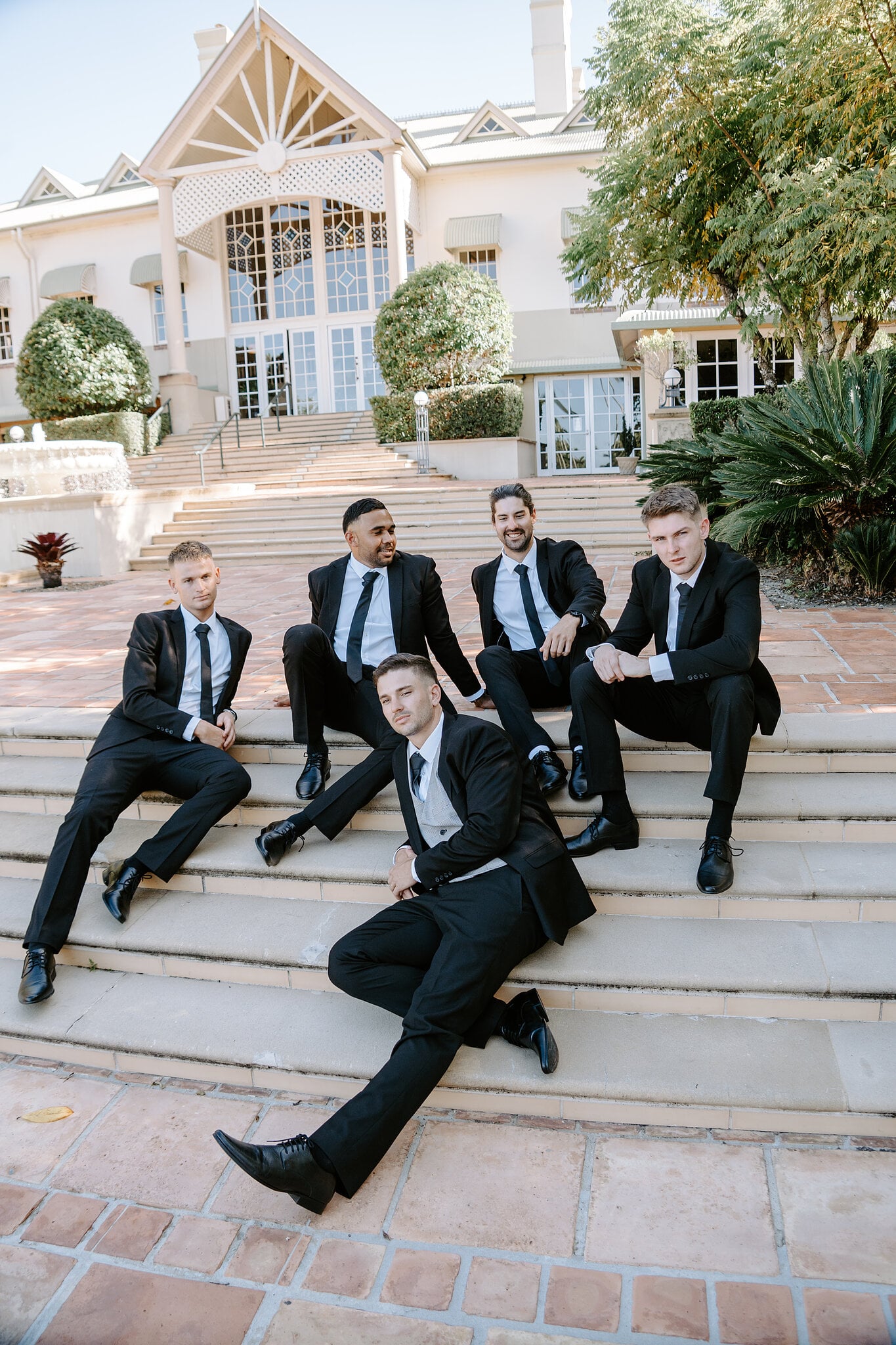 Lane and his groomsmen lounge on the sandstone steps below the main house at InterContinental Sanctuary Cove.