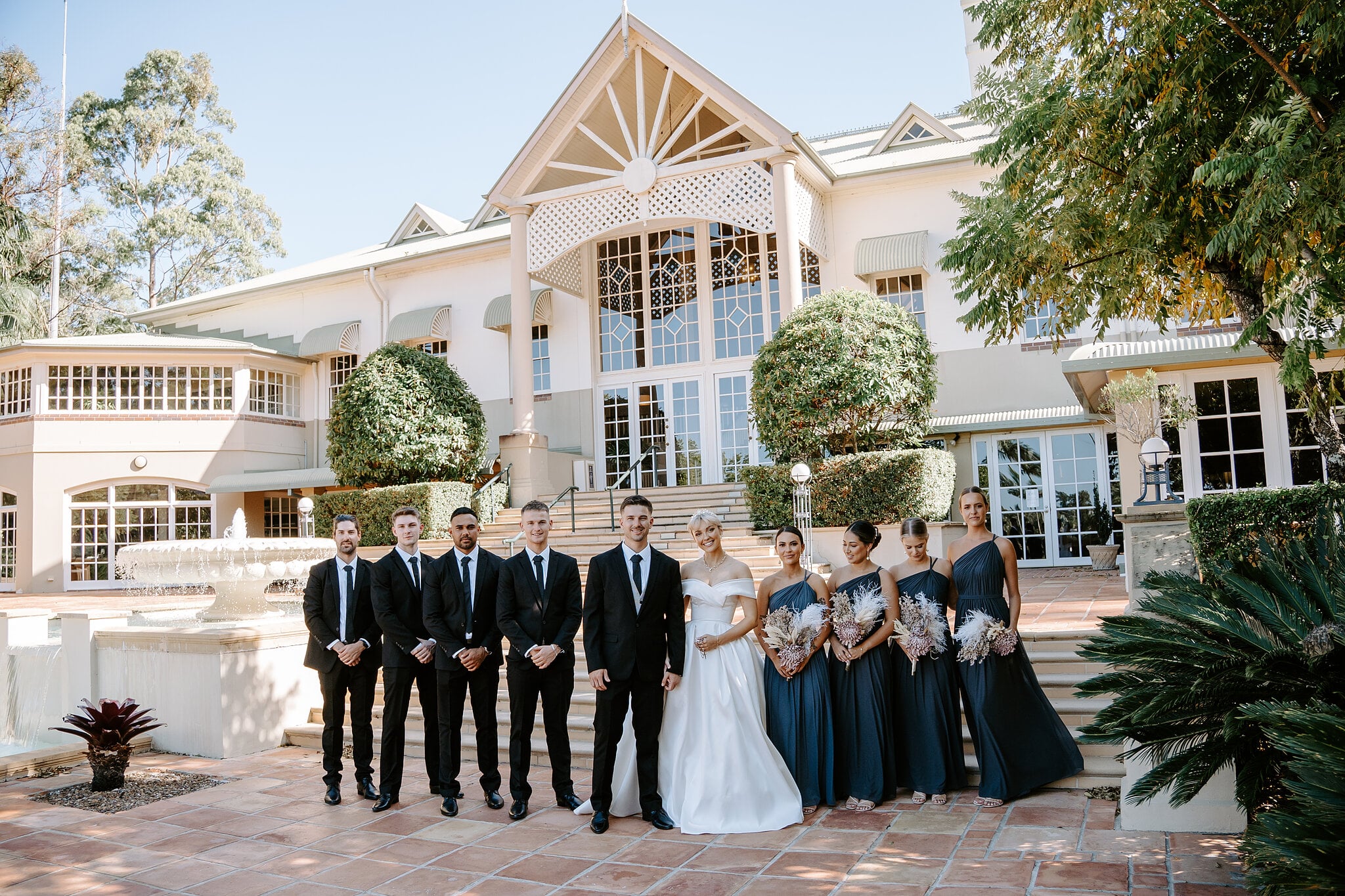 The full bridal party lines up in front of the grand main house at InterContinental Sanctuary Cove.