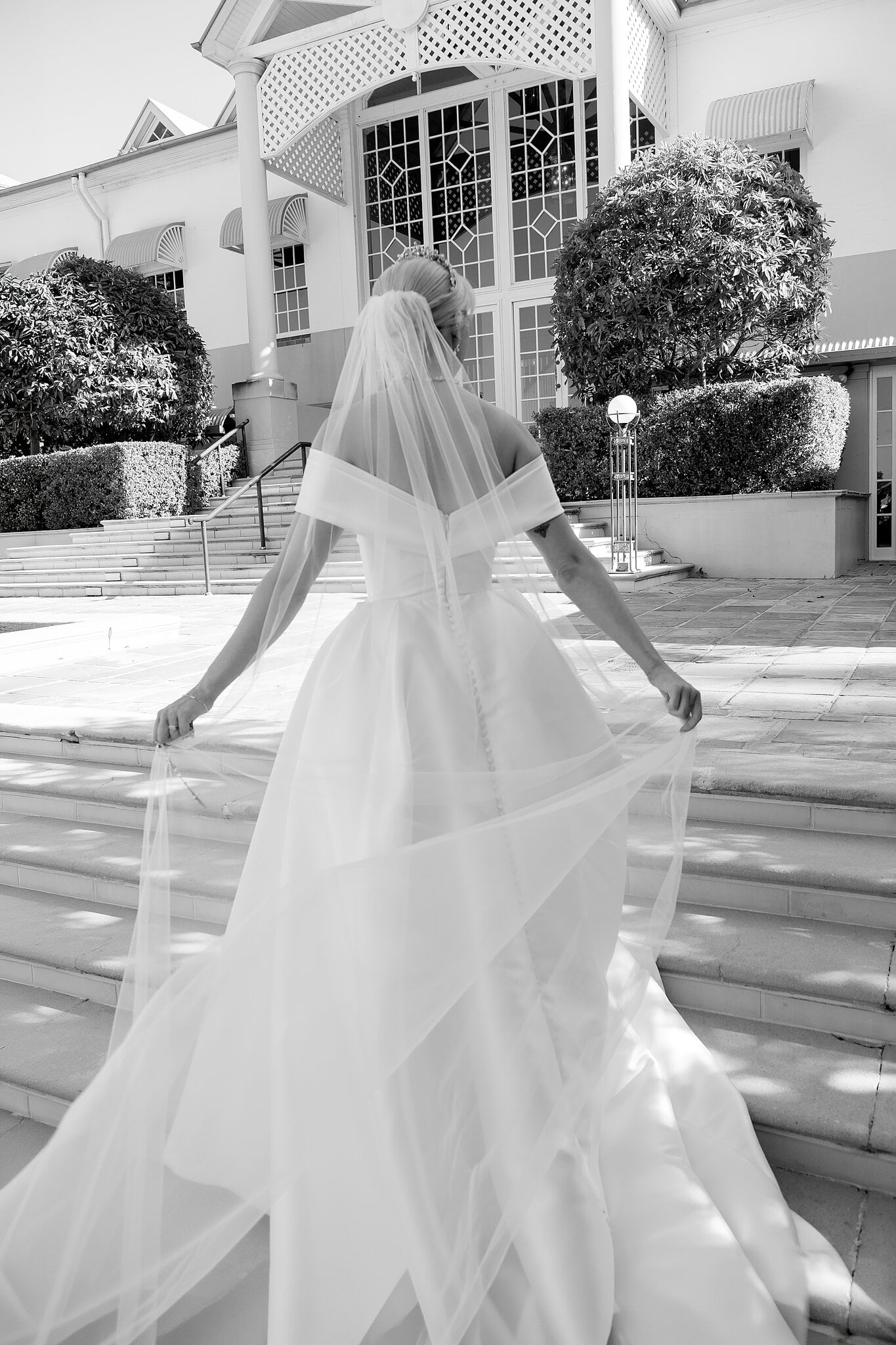 Ashley climbs the sandstone steps towards the main house, her veil trailing behind her.