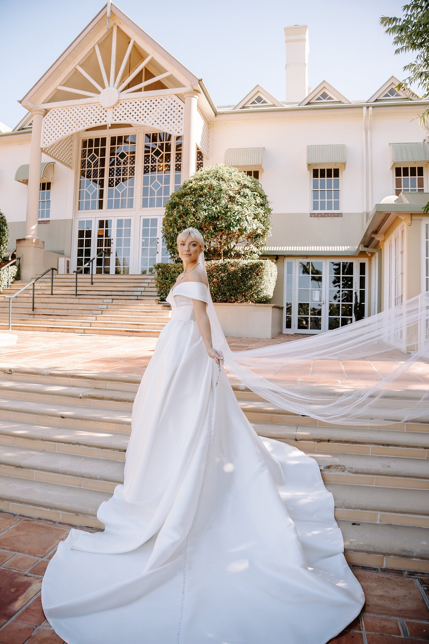 Ashley’s veil catches the breeze on the steps of the main house at InterContinental Sanctuary Cove.