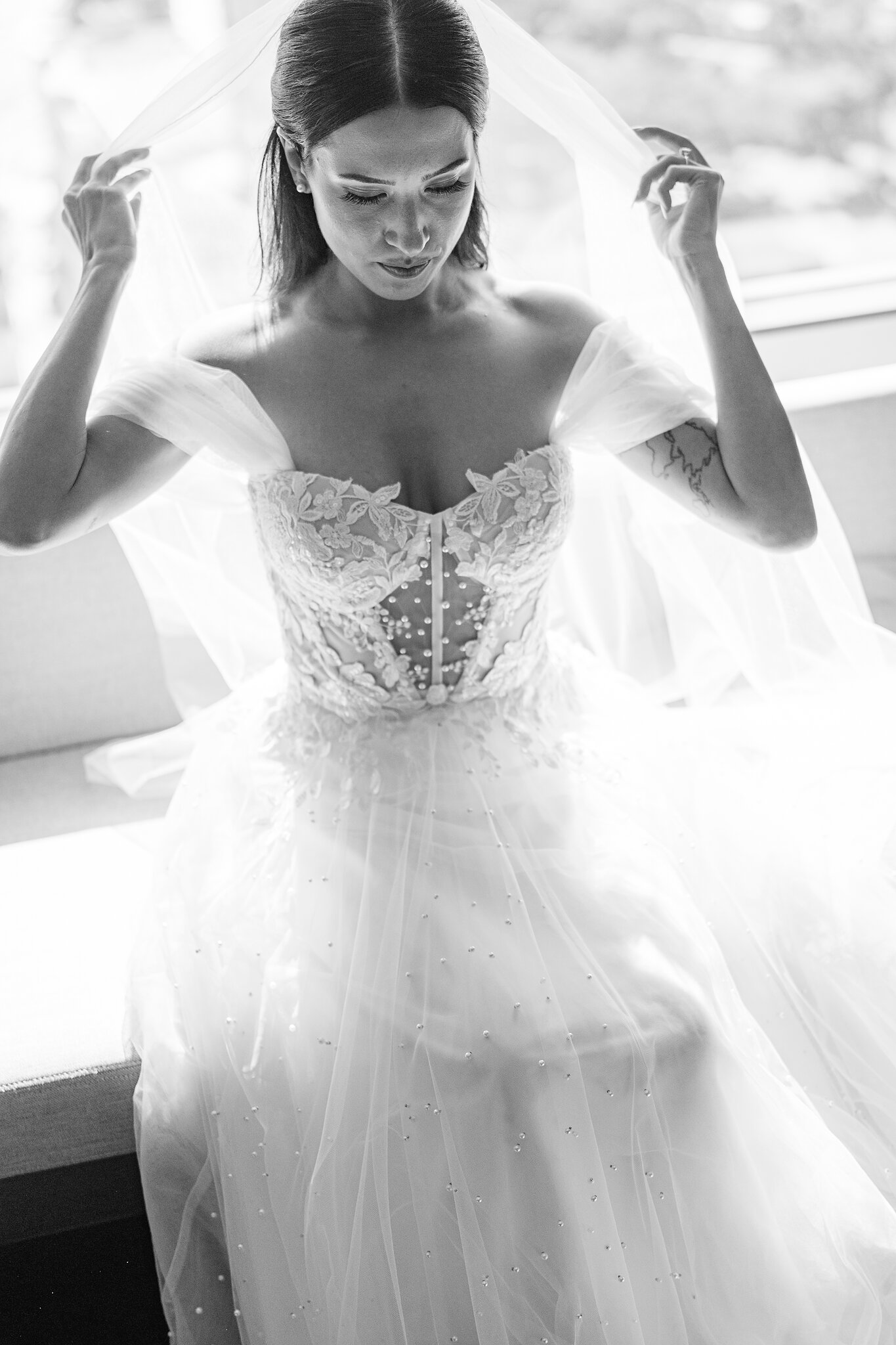 Alexa lifts her veil into place, the lace bodice catching the morning light.