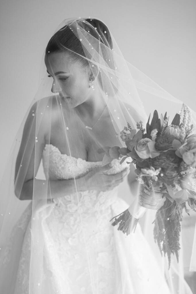 The bride beneath her pearl-studded veil, bouquet in hand, at Meadowbank Estate