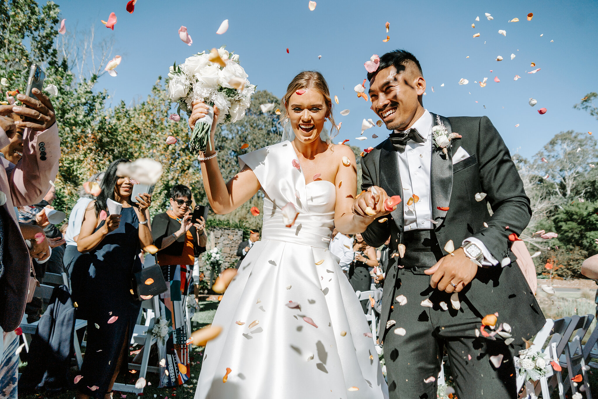 Rose petals fly as Georgie and Johnny laugh their way back down the aisle.