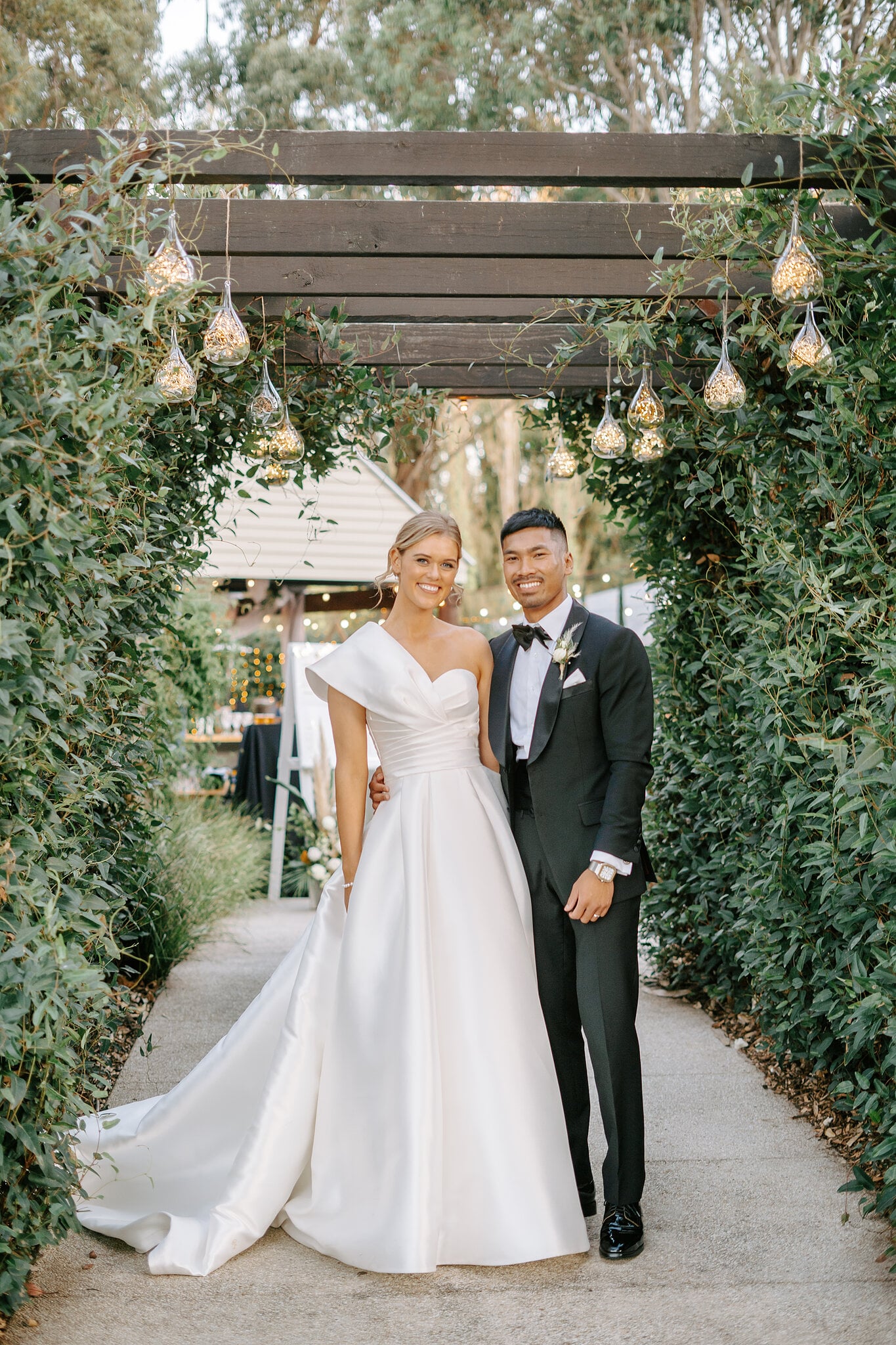 Georgie and Johnny stand under the vine-covered pergola hung with glass lights at Mercure Ballarat.
