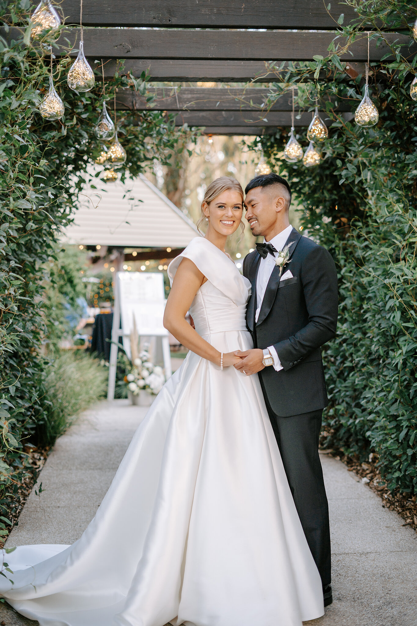 Georgie and Johnny hold each other close beneath the leafy pergola at Mercure Ballarat.