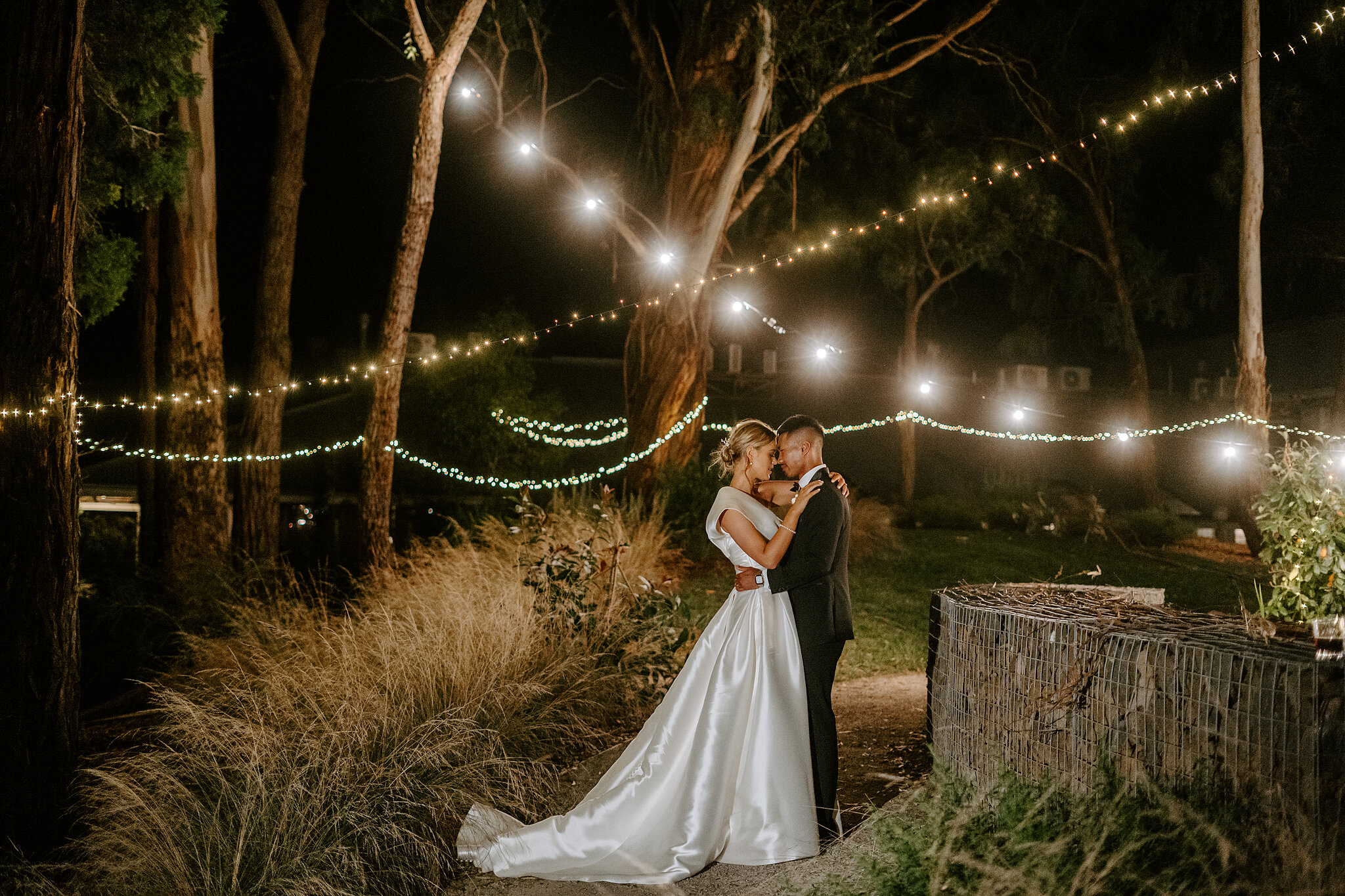 A night portrait of Georgie and Johnny among the grasses and festoon lights at Mercure Ballarat.