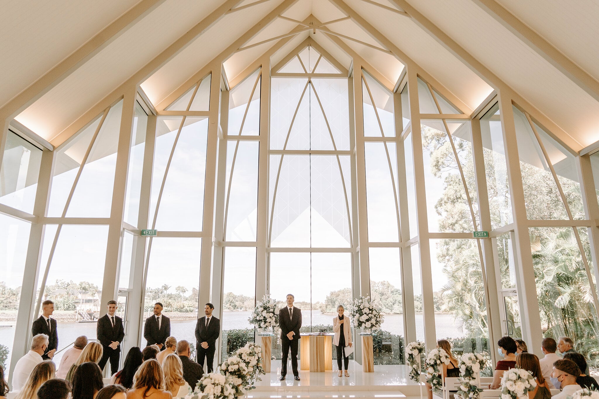 Guests fill the glass-walled chapel at InterContinental Sanctuary Cove as Lane waits by the river view.