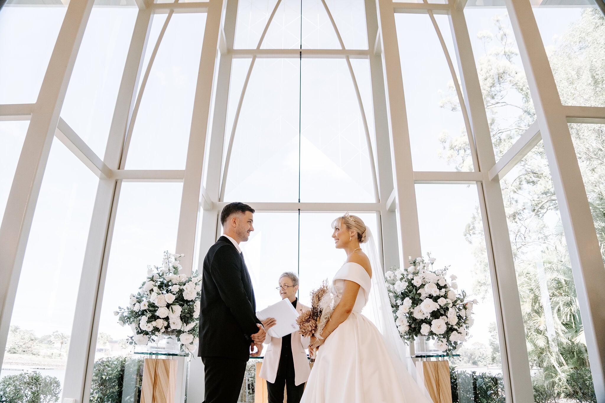 Ashley and Lane face each other for their vows beneath the chapel’s soaring glass arches.