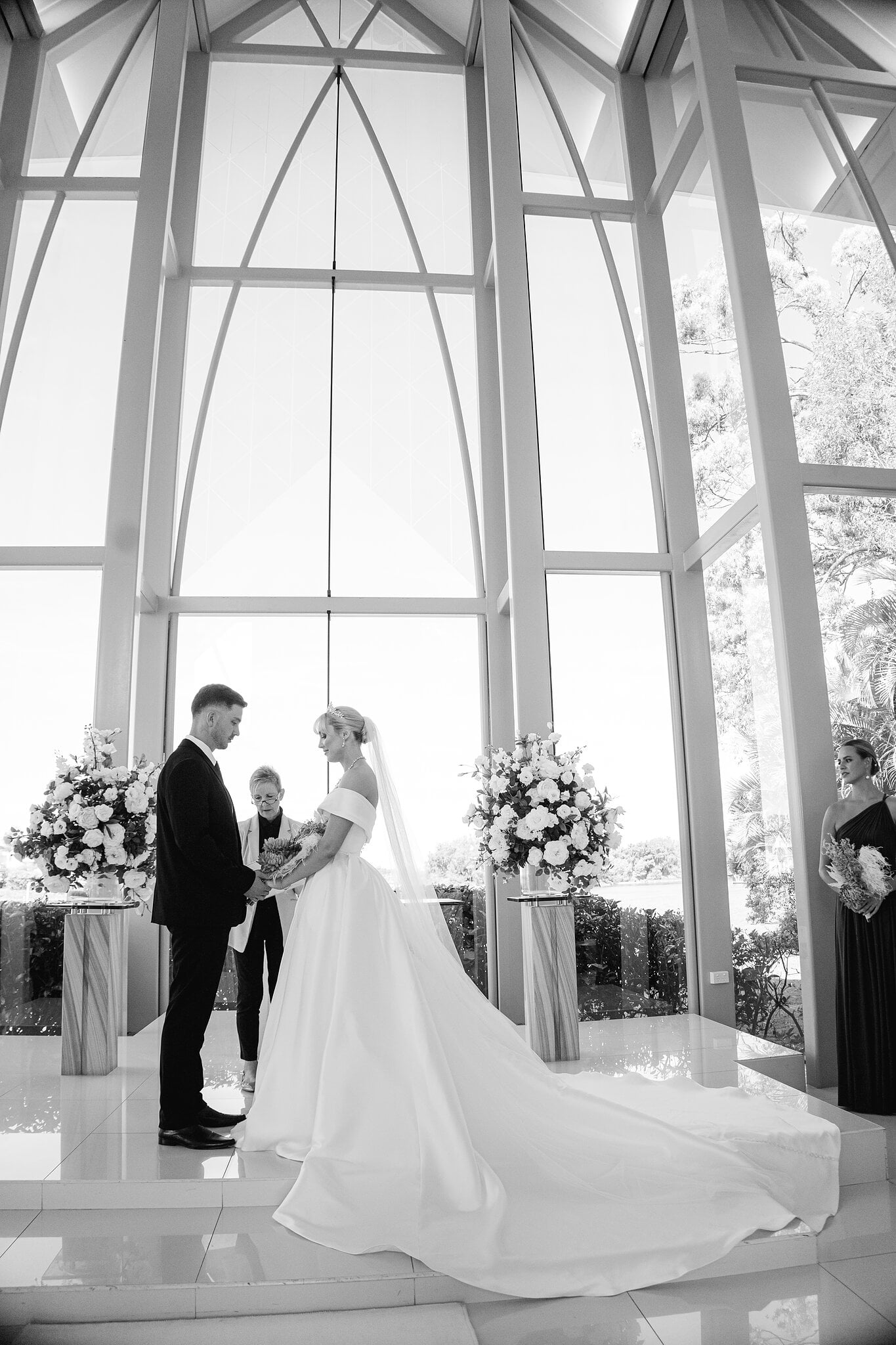 Ashley and Lane hold hands through their vows, her train spread across the white chapel floor.
