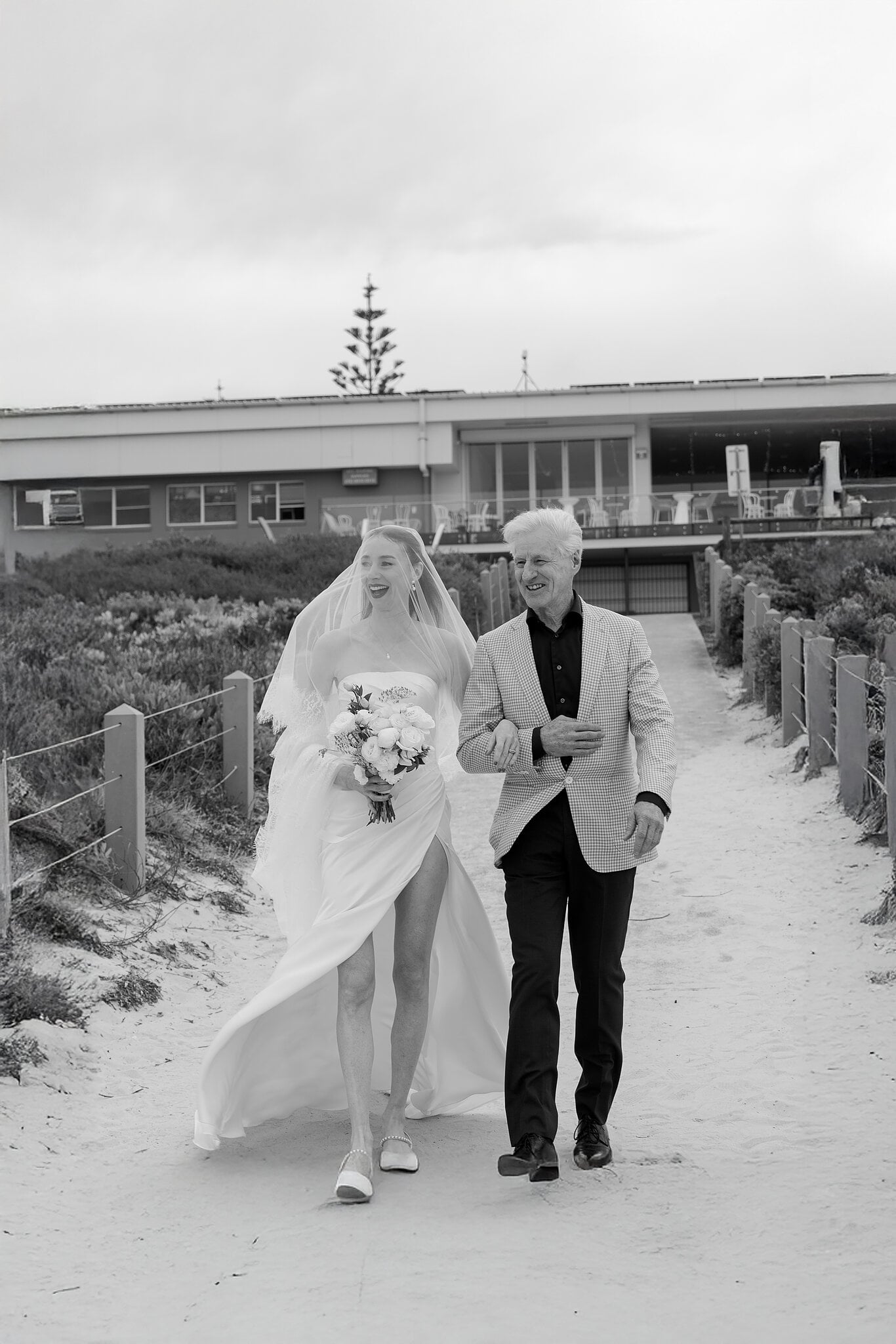 Michele walks down the beach track with her dad, Horizons South Maroubra behind them.