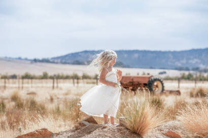A little girl in a white dress on a windswept hilltop, from our wedding photographer portfolio