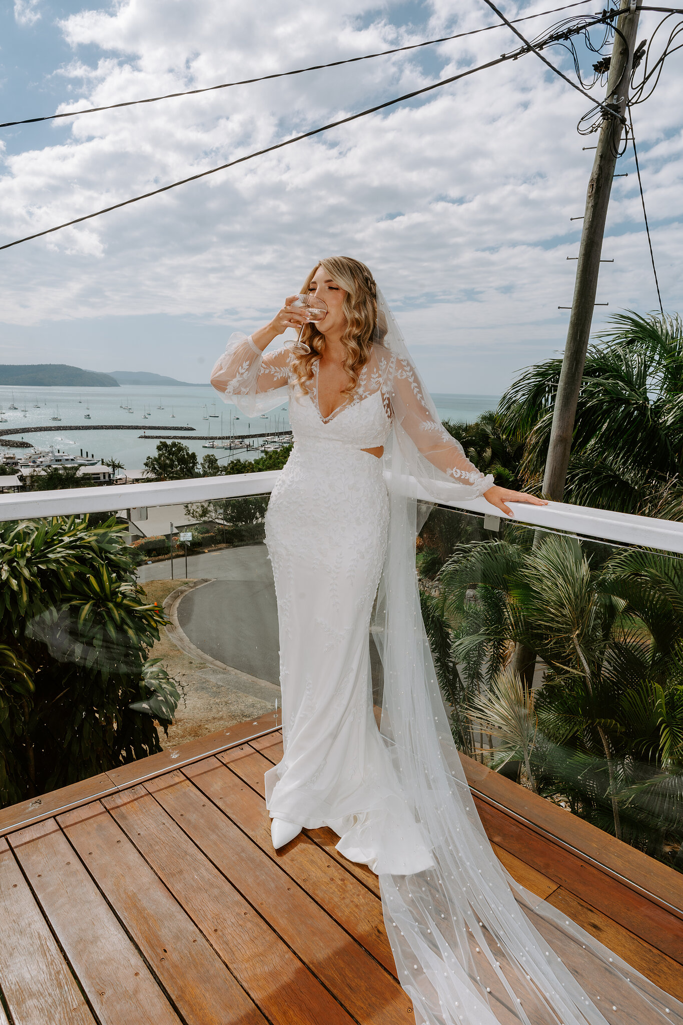 Anna takes in the moment on the deck in her lace gown, the bay and hills behind her.