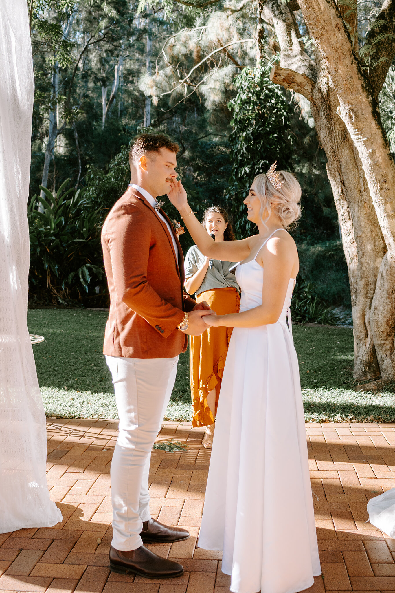 Amanda touches Patrick’s face as they hold hands at the front of their garden ceremony.