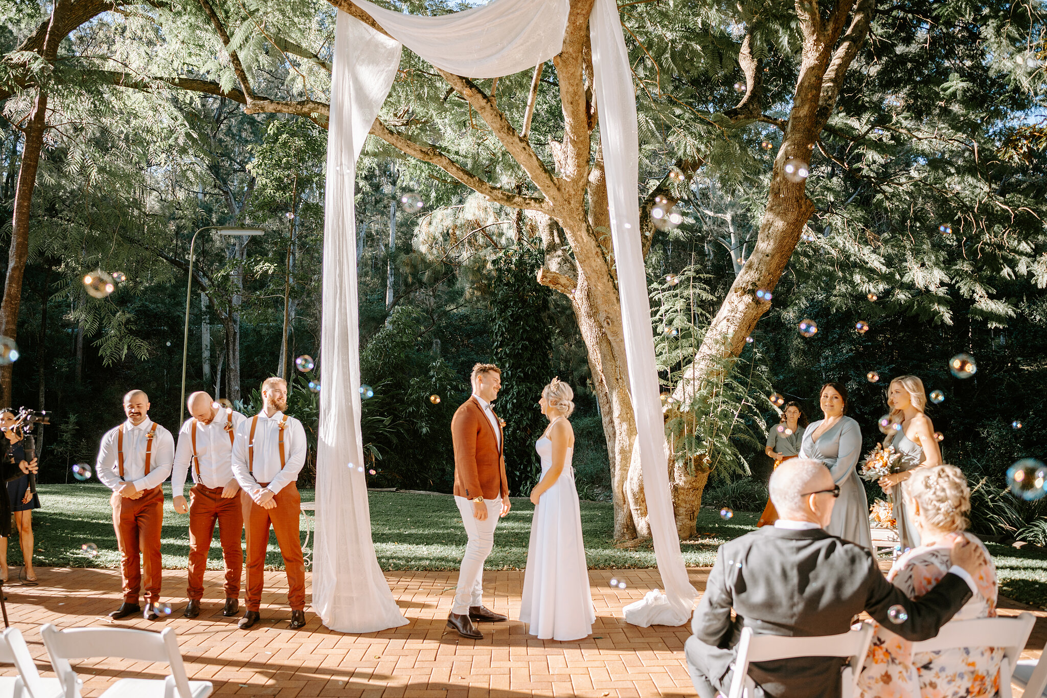 Bubbles drift across the ceremony as Amanda and Patrick stand together under the white drapes.