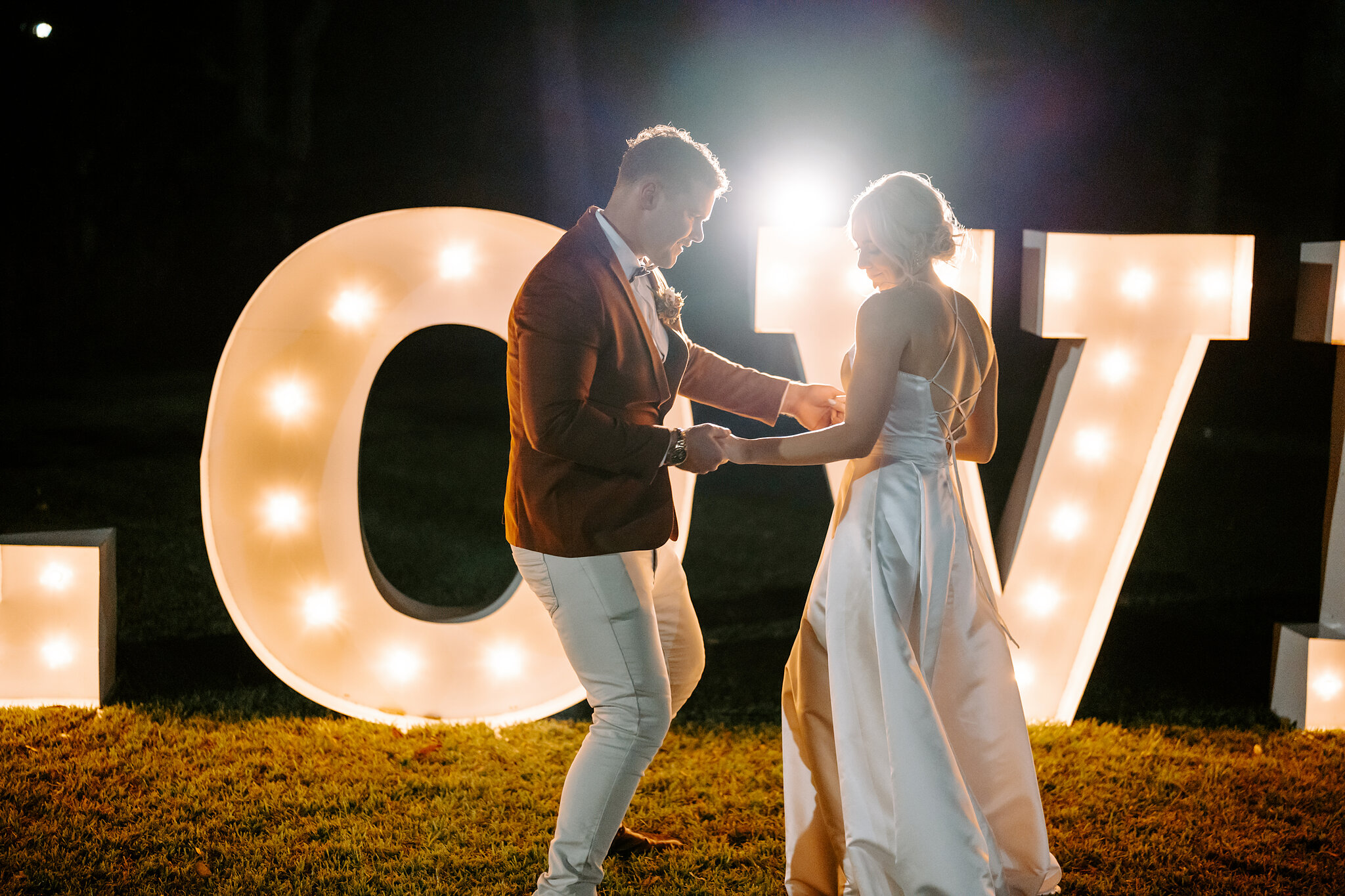 Patrick swings Amanda between the glowing O and V of the LOVE letters.