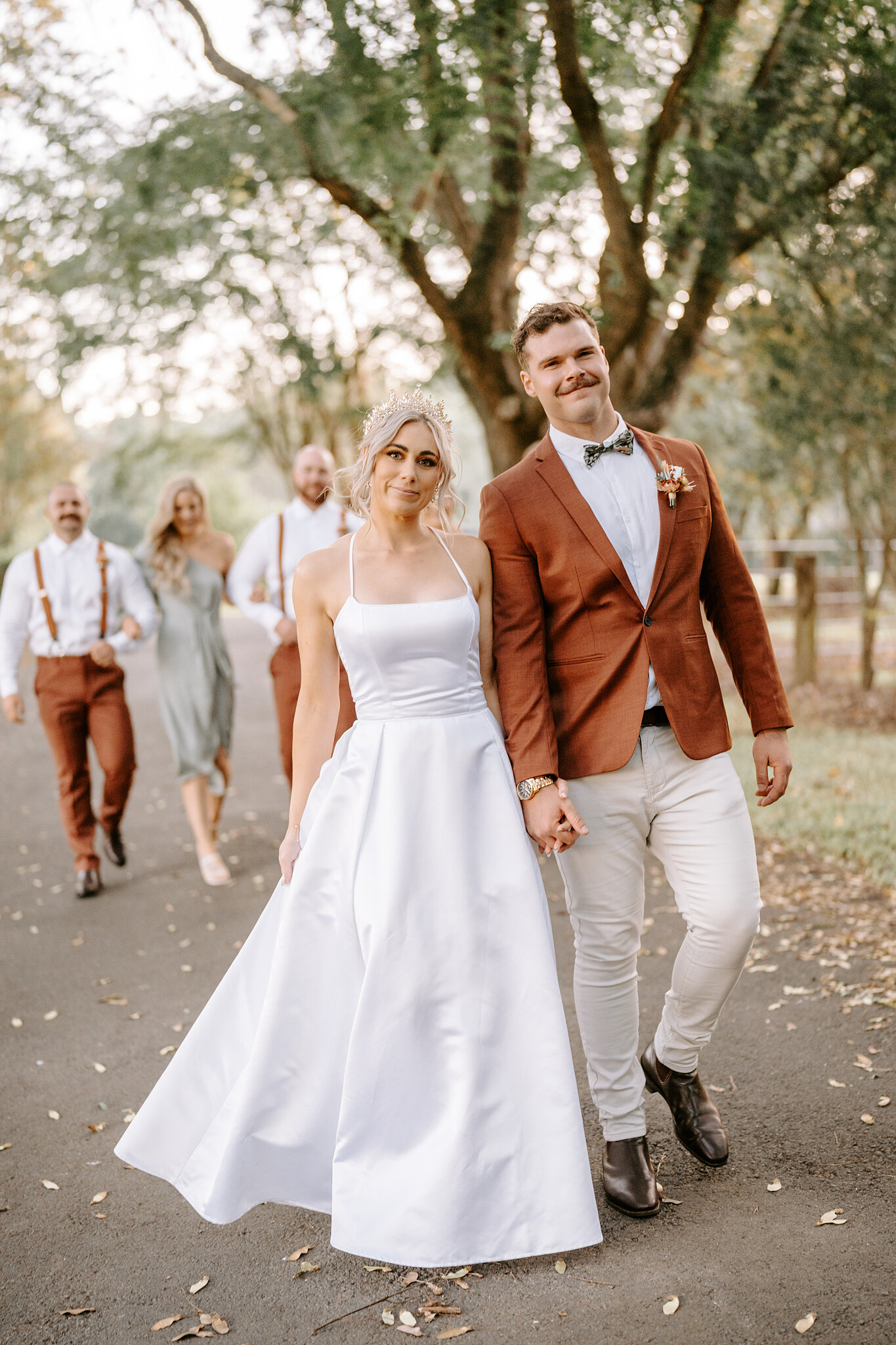 Amanda and Patrick walk hand in hand down the driveway with their bridal party following behind.