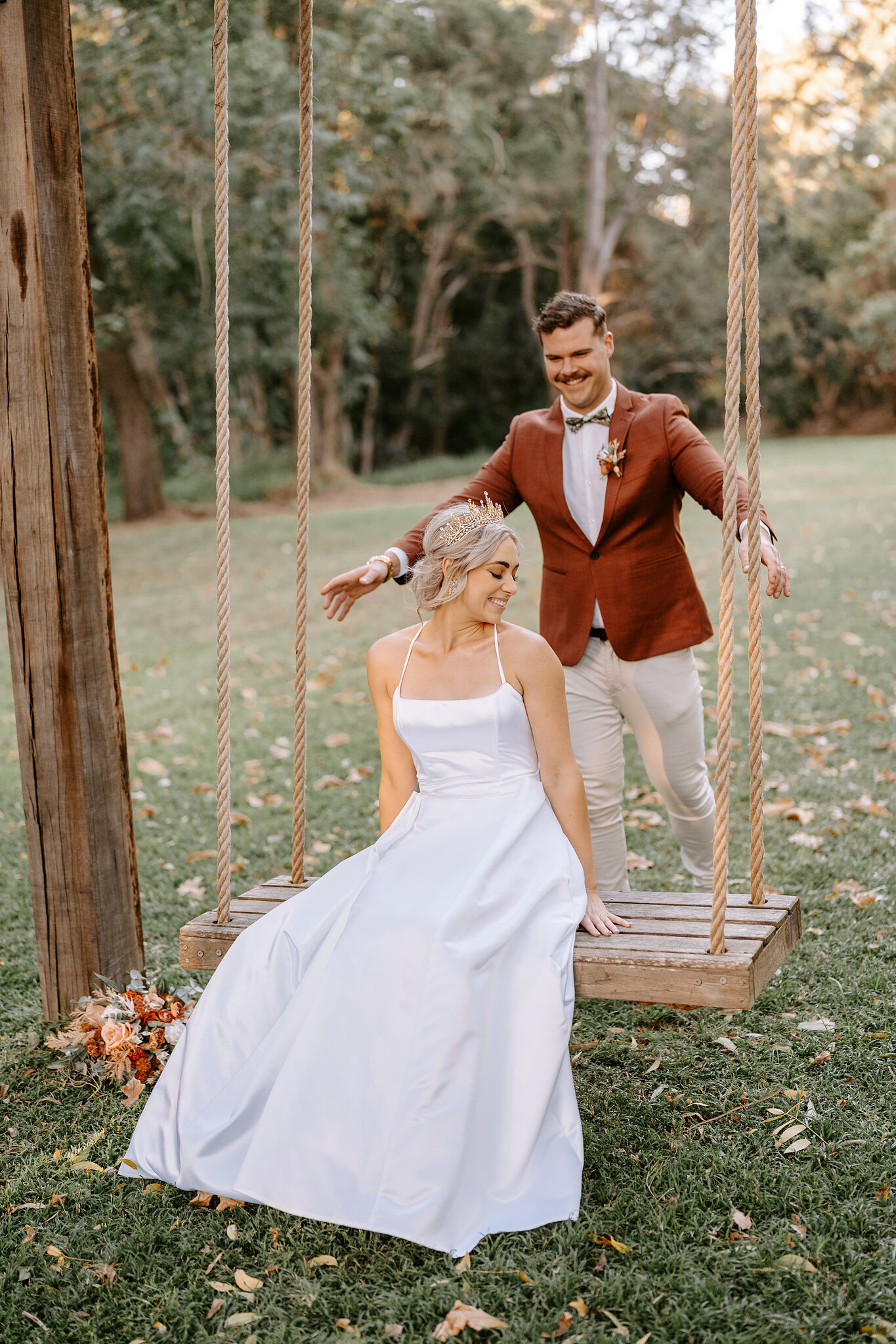 Patrick leans in to push the swing as Amanda laughs on the timber seat.