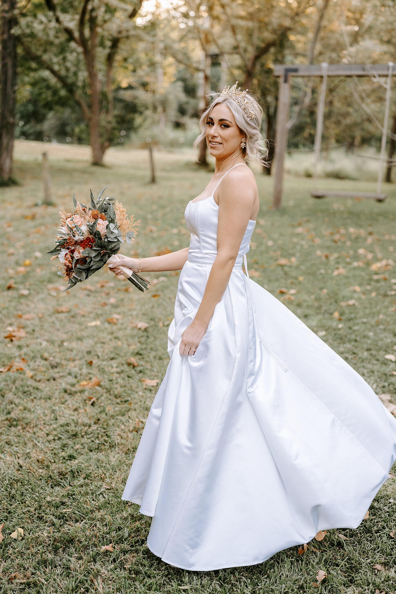 Amanda twirls her satin skirt across the autumn leaves, the rope swing behind her.