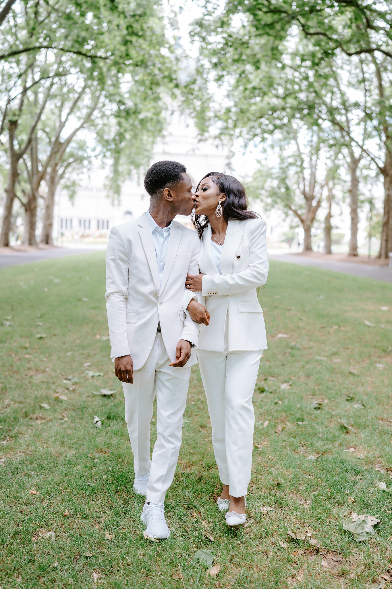 Pearl kisses Allen’s cheek as they stroll arm in arm down a tree-lined avenue in Carlton Gardens.