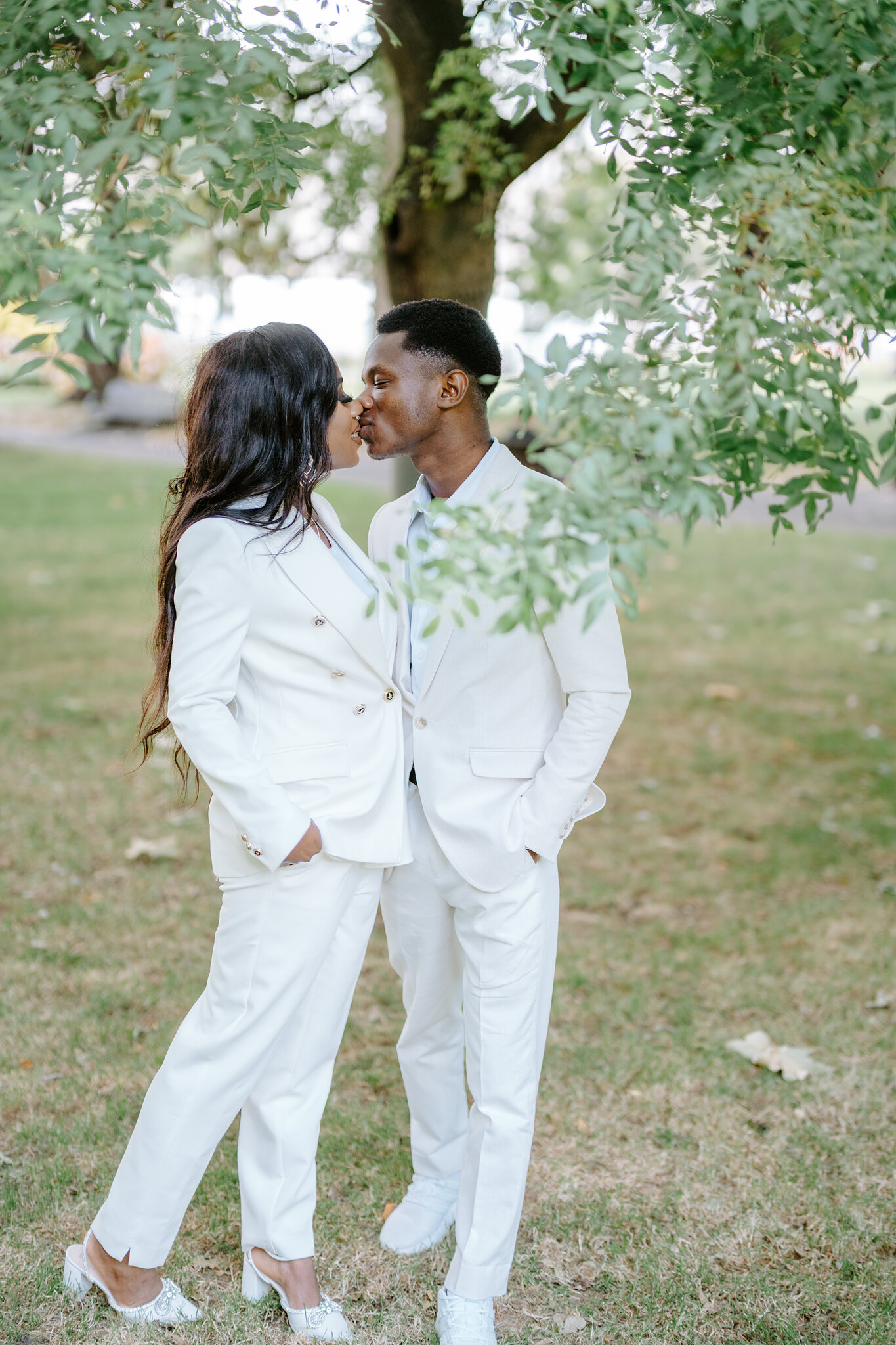 Pearl and Allen kiss beneath a low leafy branch on the Carlton Gardens lawn.