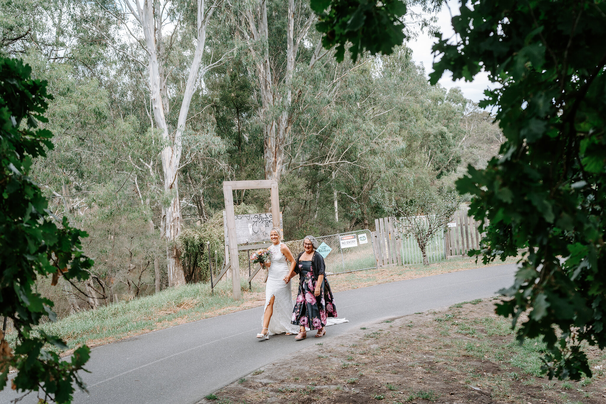 Emma and her mum walk arm in arm down the farm track under the gums.