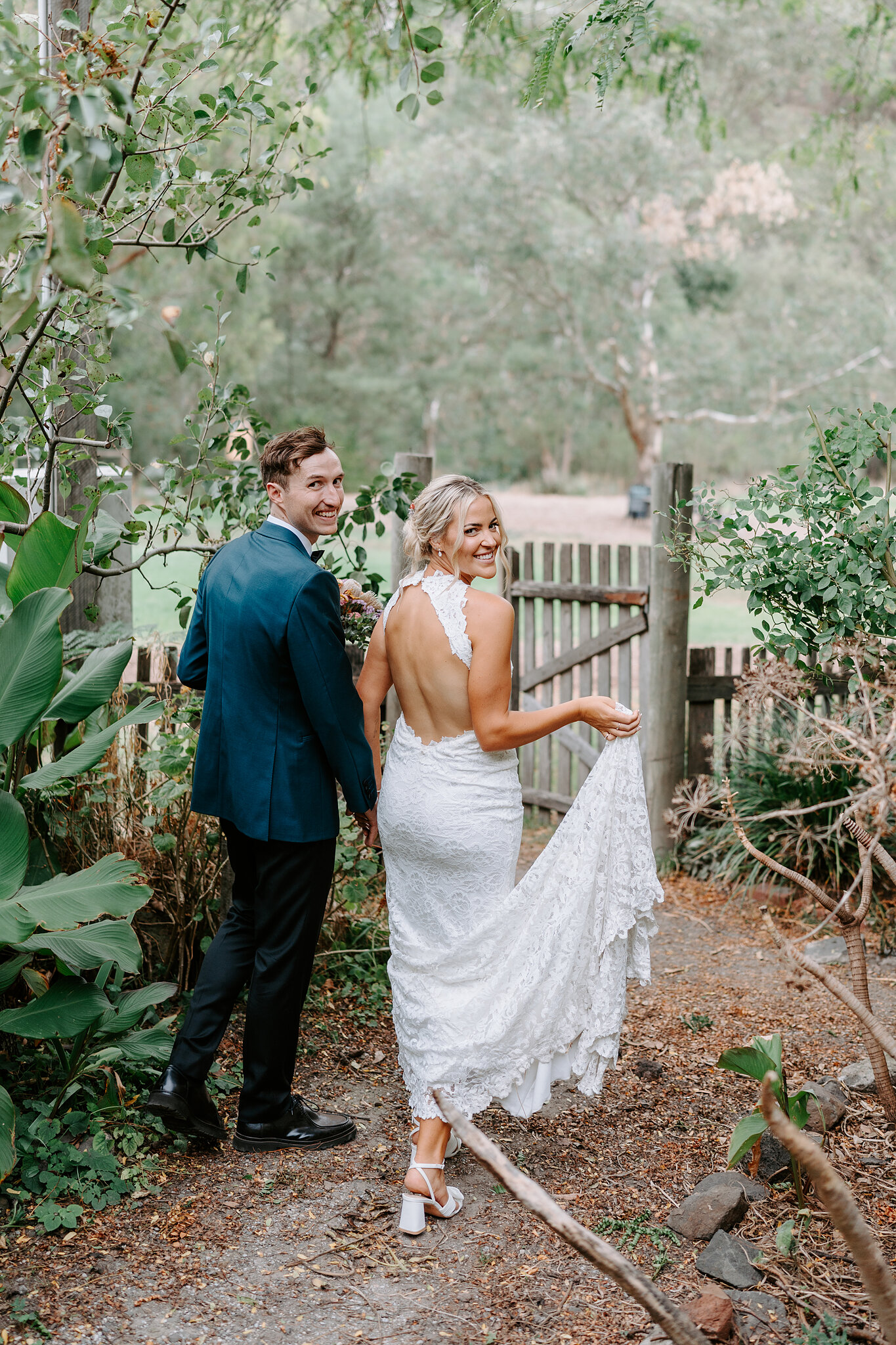 Emma lifts her train as she and George walk the garden path hand in hand.