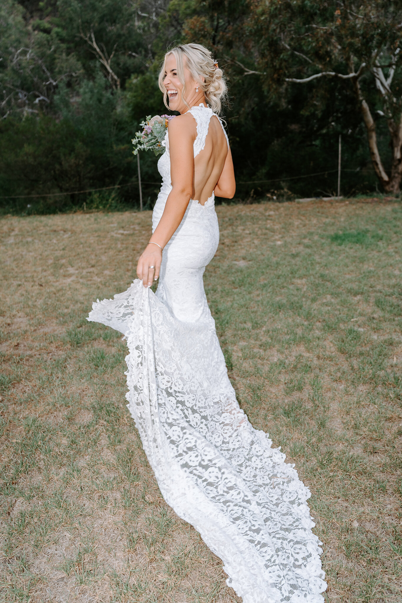 Emma looks back over her shoulder, sweeping her lace train across the grass.