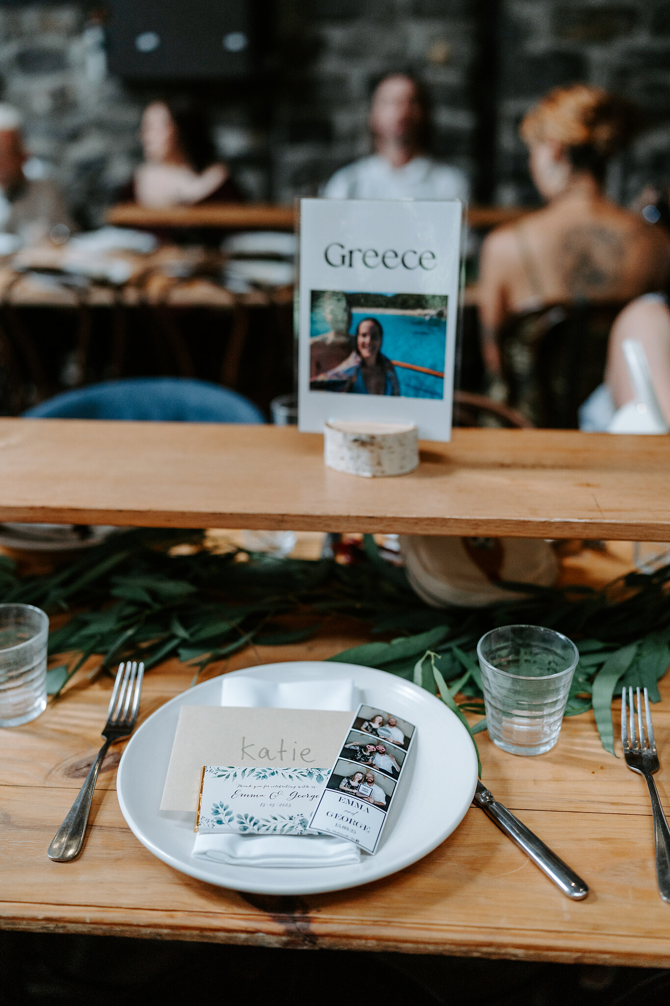 A Greece table card with a travel photo on the long tables in the Barn.